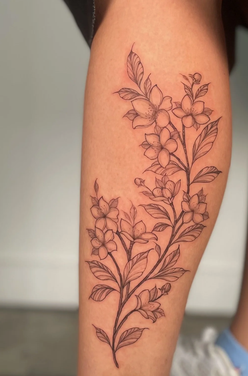 A tattoo of a floral design with multiple flowers and leaves on a person's arm.
