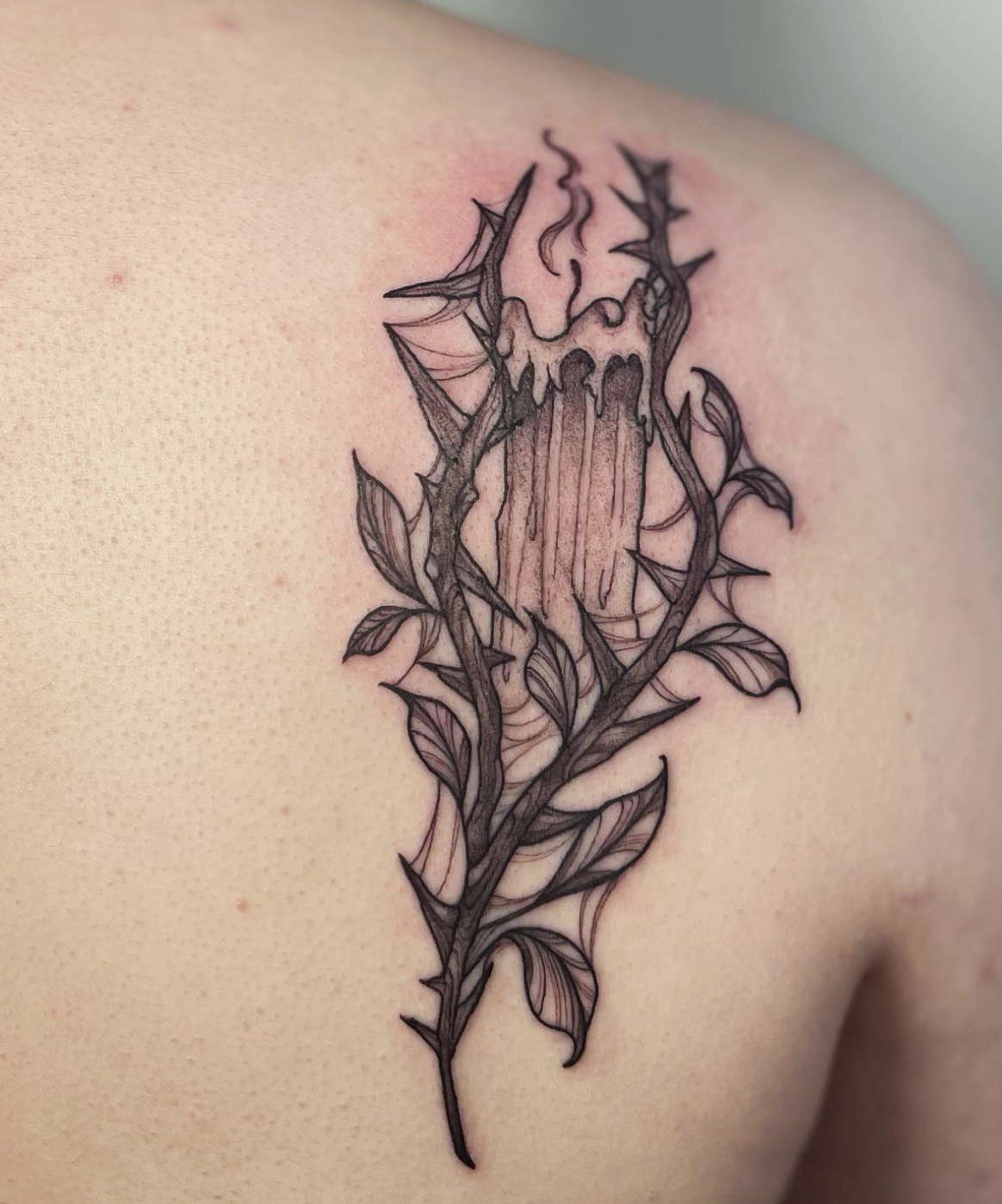 A tattoo of a melting candle with a flame surrounded by thorny branches and leaves, inked on someone's skin.