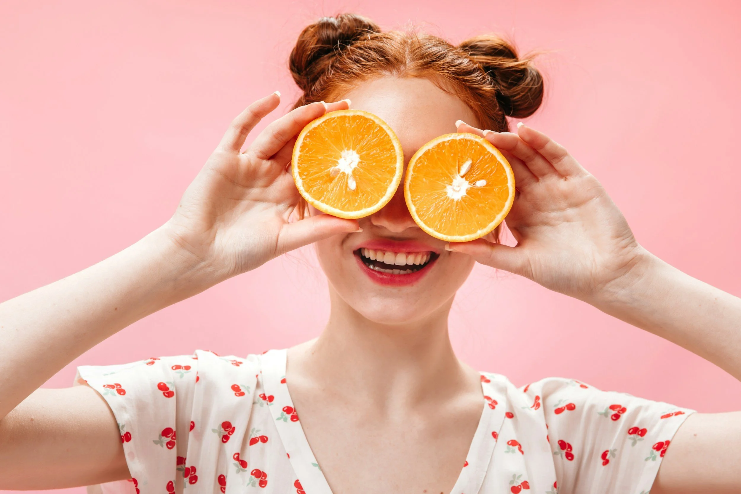 Woman holding oranges over her eyes