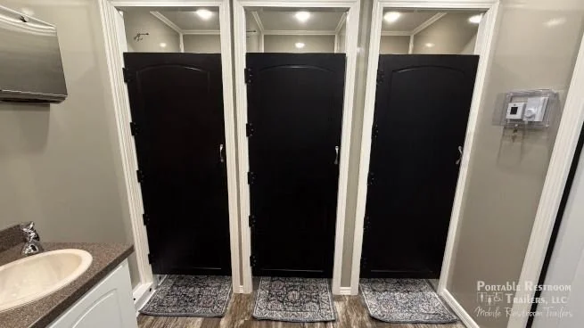 Men's restroom interior with private toilet stalls, urinals and sinks in a 10-stall luxury restroom trailer