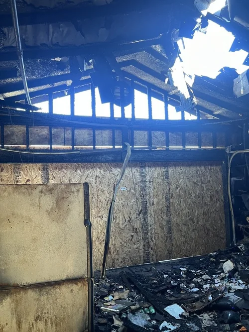 Interior of a charred and damaged building with a partially destroyed roof.