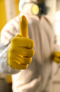Image of person in a Hazmat suit, standing, giving a reassuring thumbs up