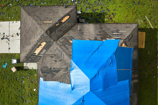 Top down view of partially burned home with roof tarping covering damage