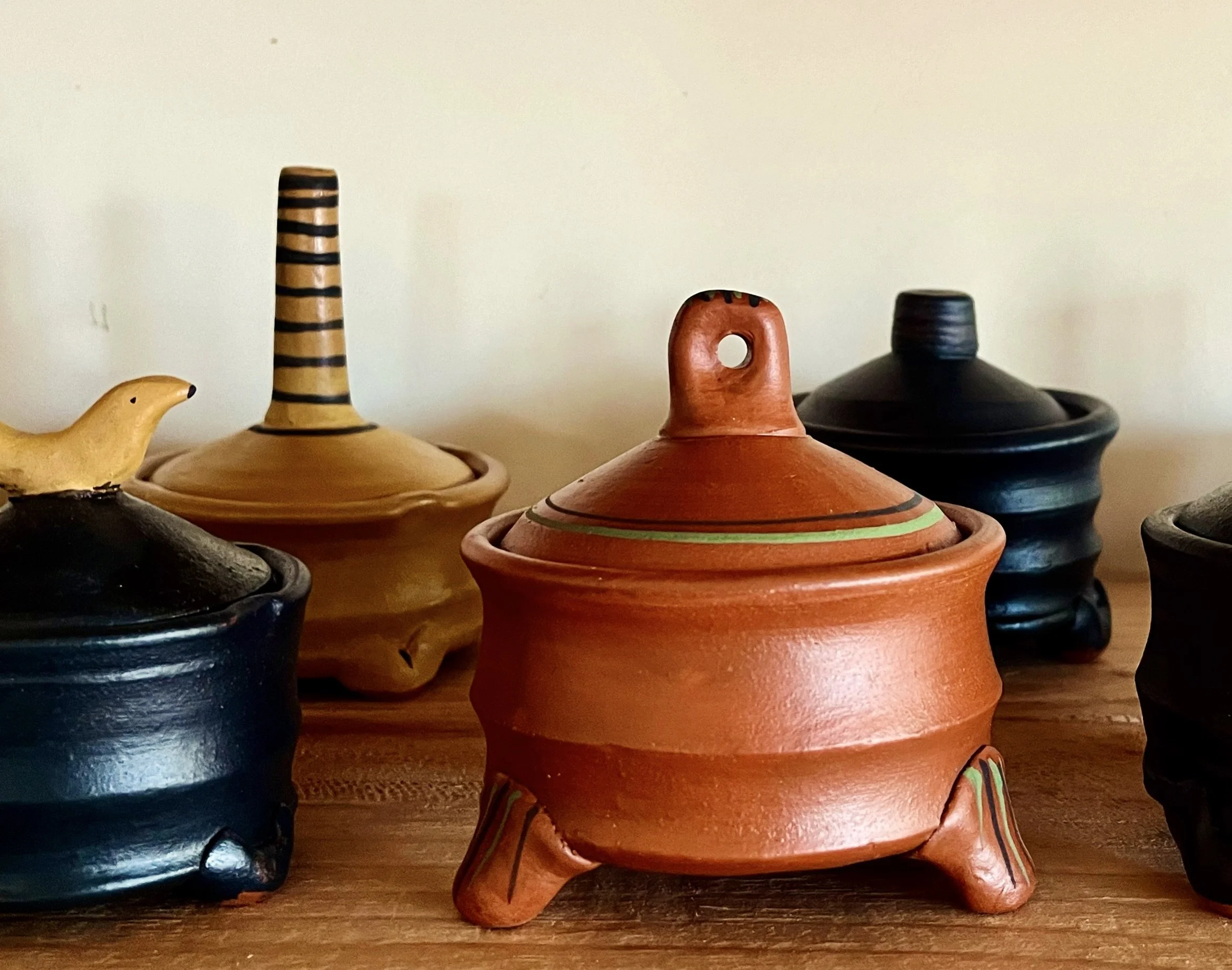 Assorted handmade pottery containers with lids on a wooden surface.