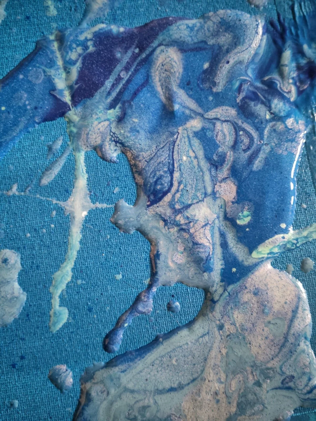 Abstract mixture of blue, purple, and white paints on a textured blue fabric background.
