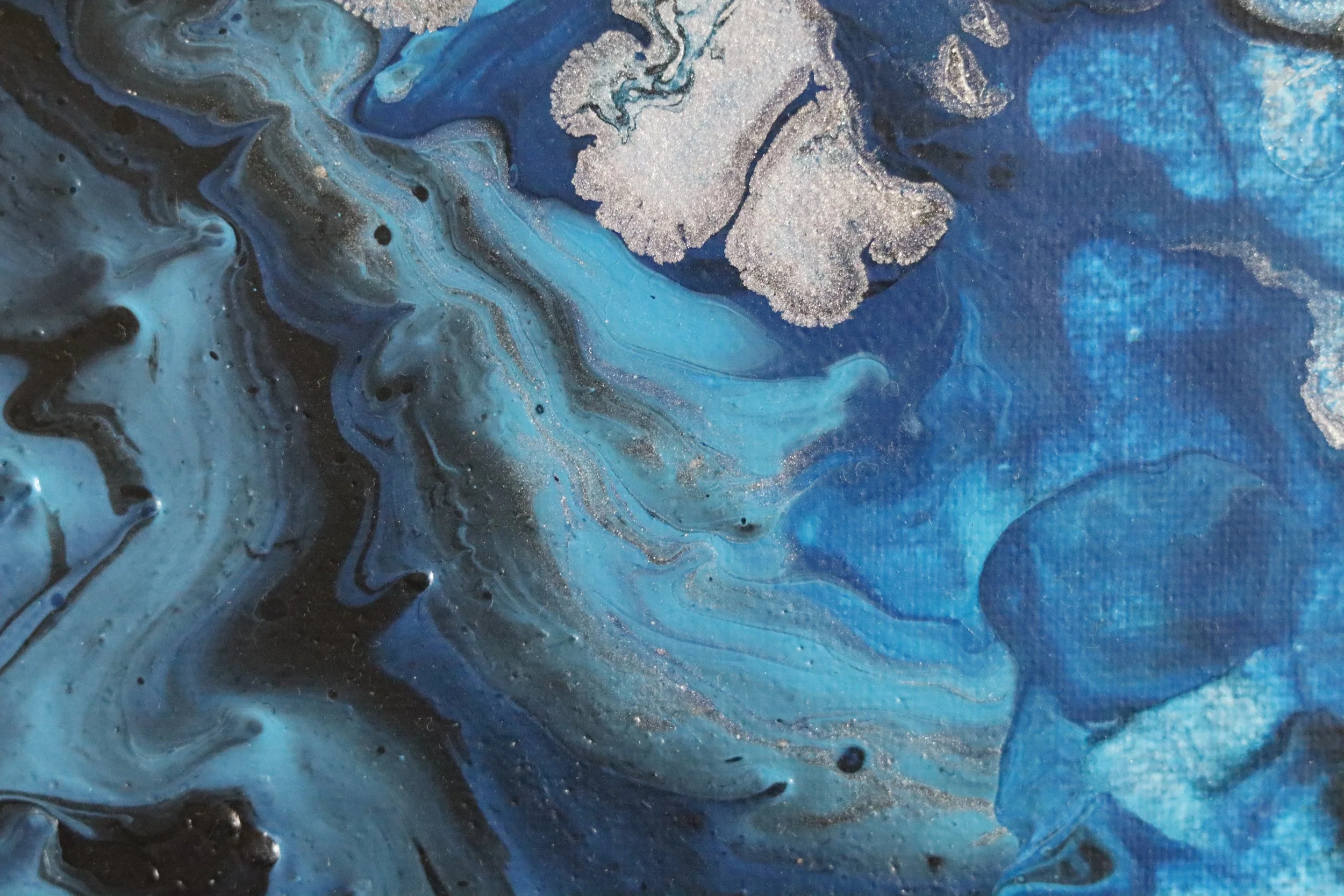 Abstract painting with swirling blue, black, gray, and gold colors.