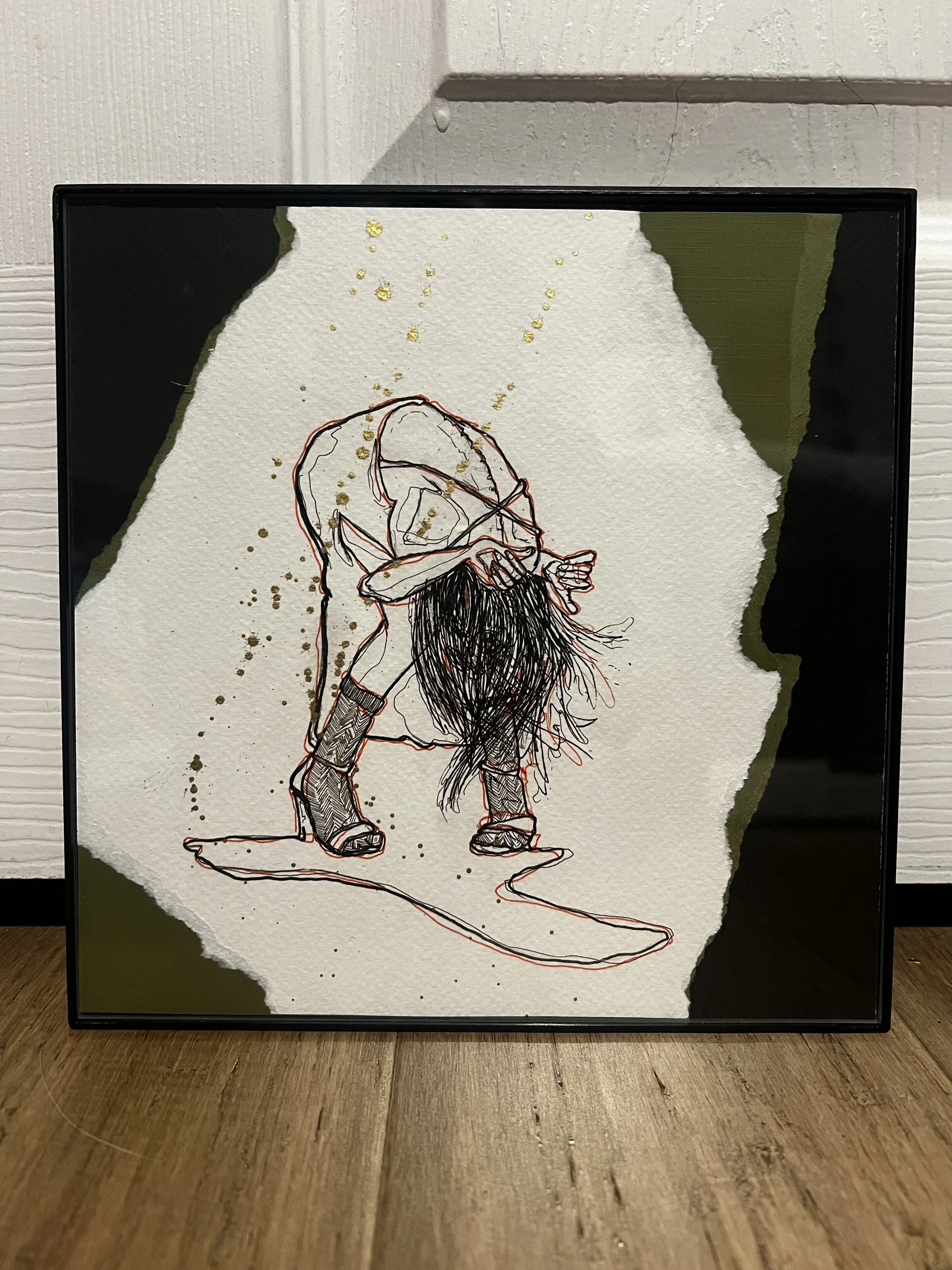 A framed print of a woman bent over, her long black hair falling forward to reveal the straps of an apron-like cloth draped across the curve of her spine.