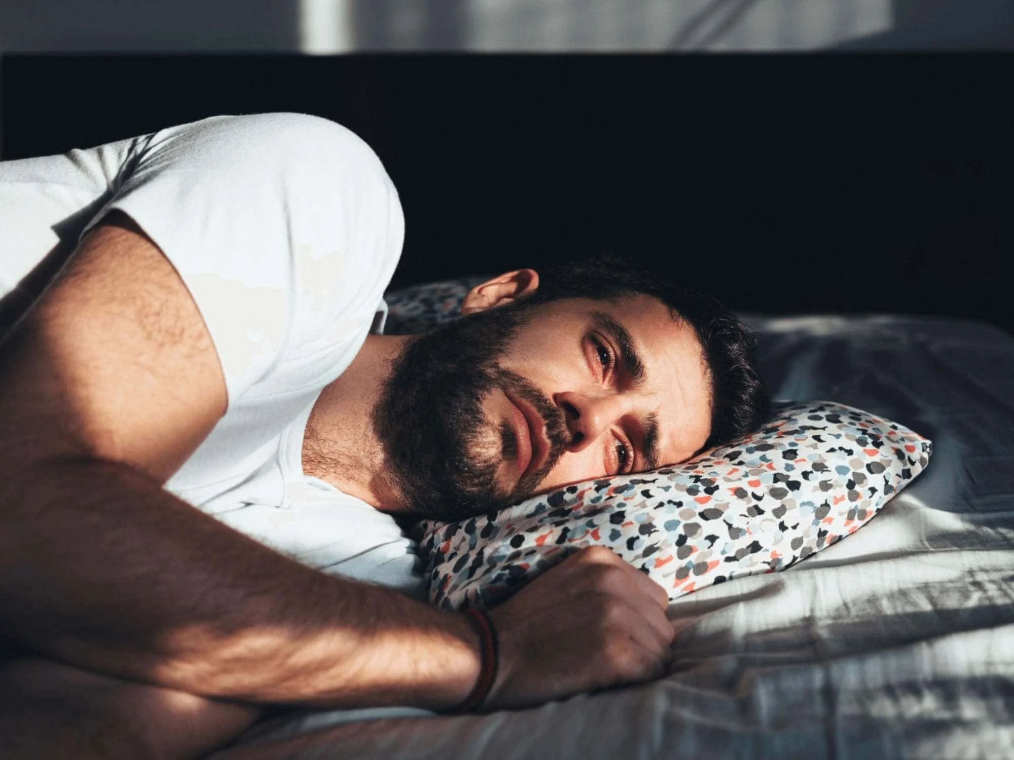 Man lying in bed experiencing symptoms of bipolar depression