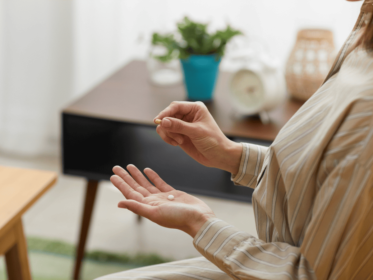 A person holding a lithium pill for bipolar disorder treatment while sitting at a desk.