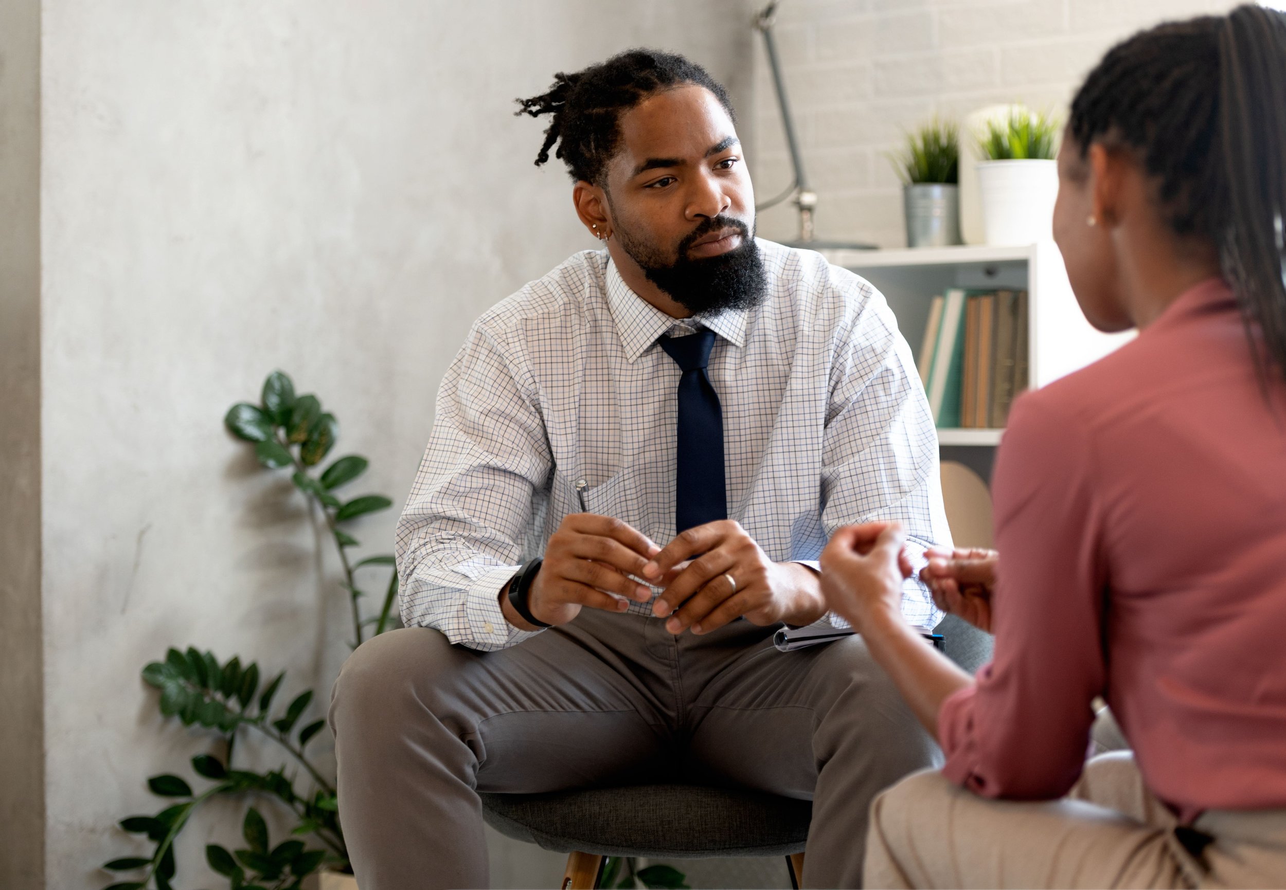 A man and woman having a serious conversation in an office setting, seated across from each other.