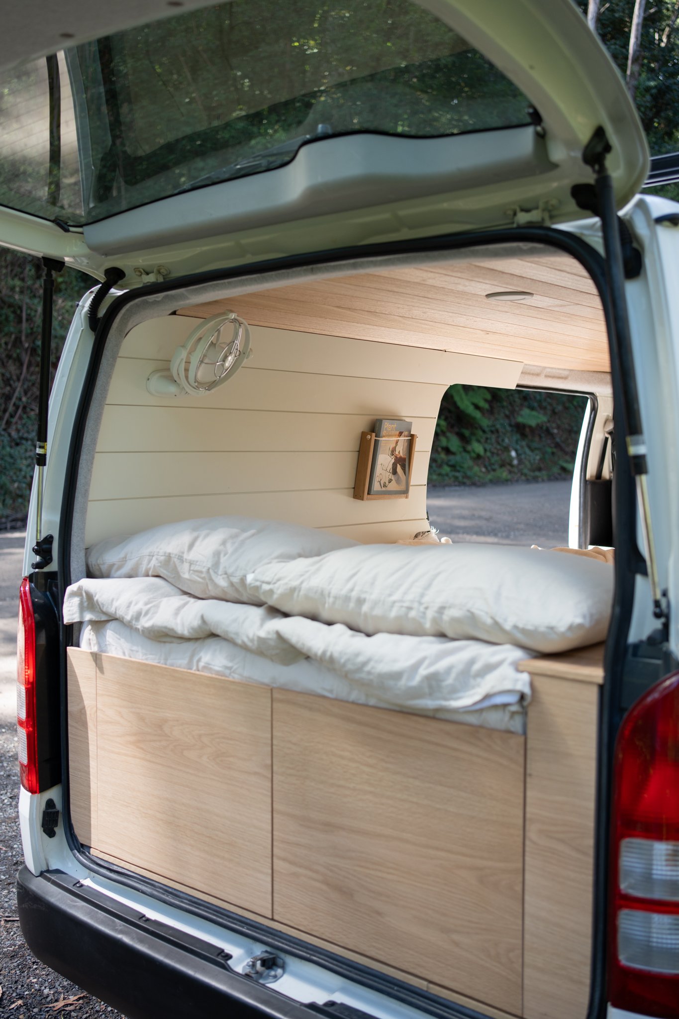 Interior of a camper van with bed and wooden wall paneling