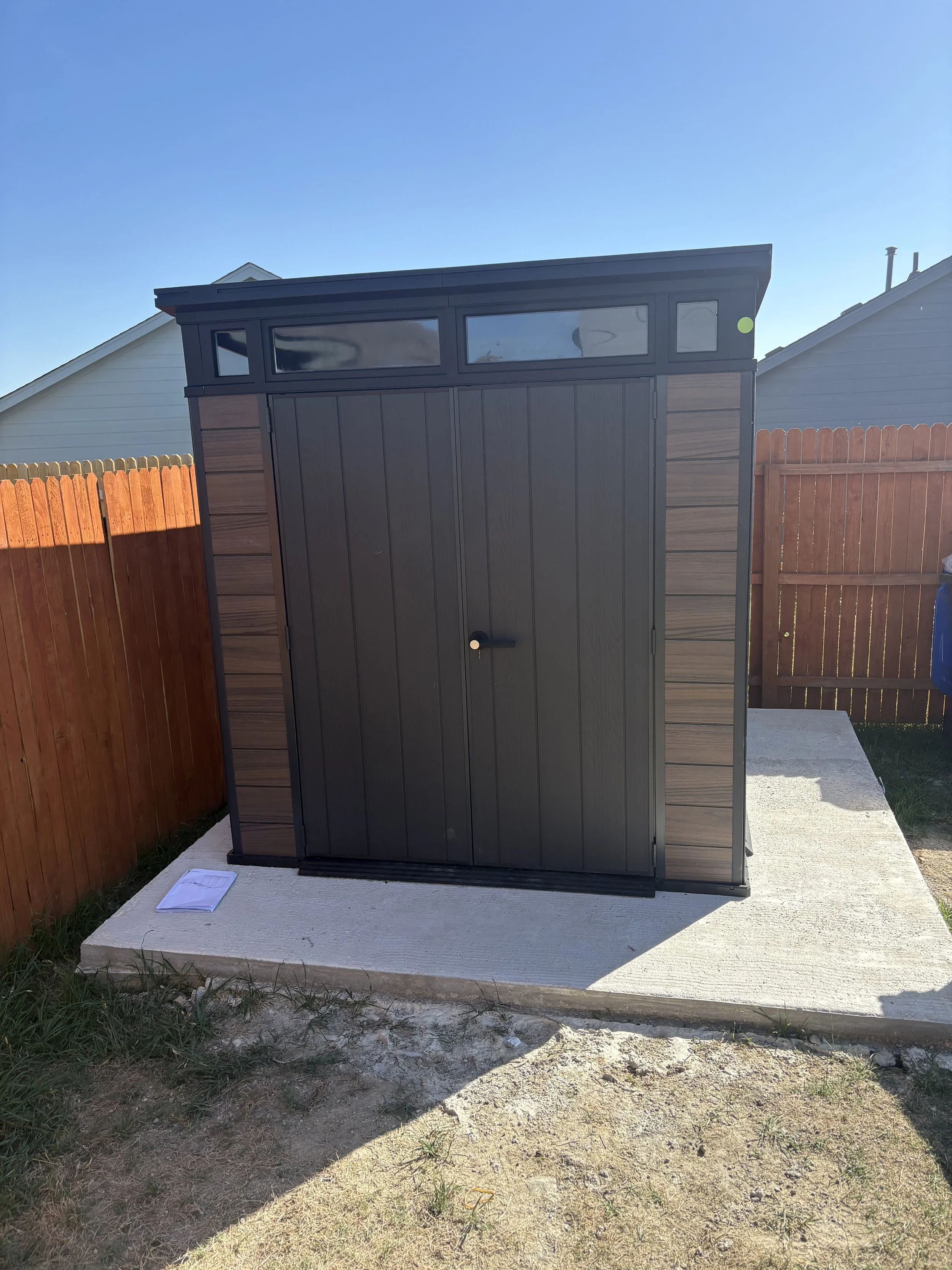 Outdoor storage shed assembled and installed securely on concrete pad.