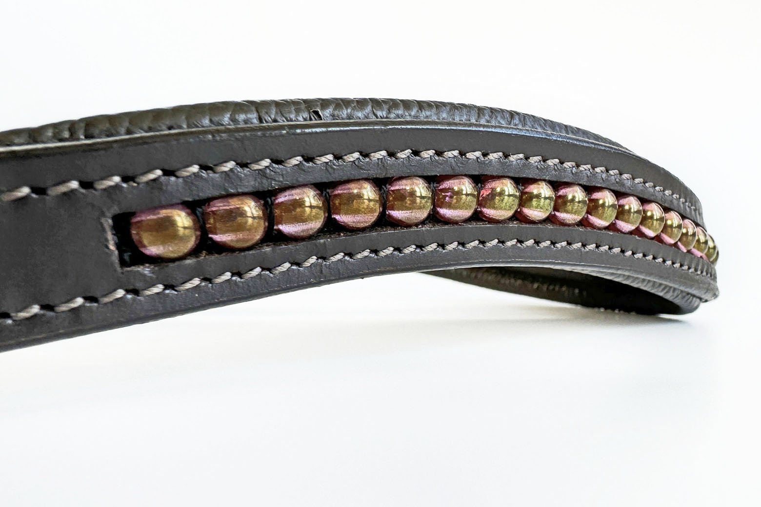 Close up of iridescent rose gold beads in a brown leather browband