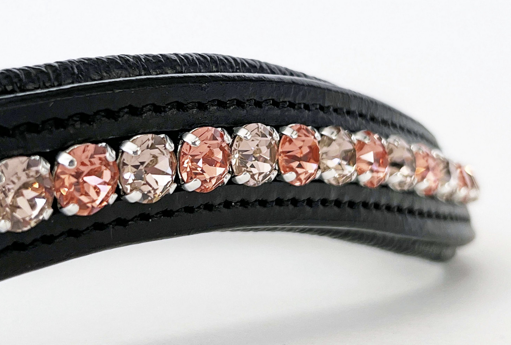 Close up of vintage rose colored crystals in a black leather browband