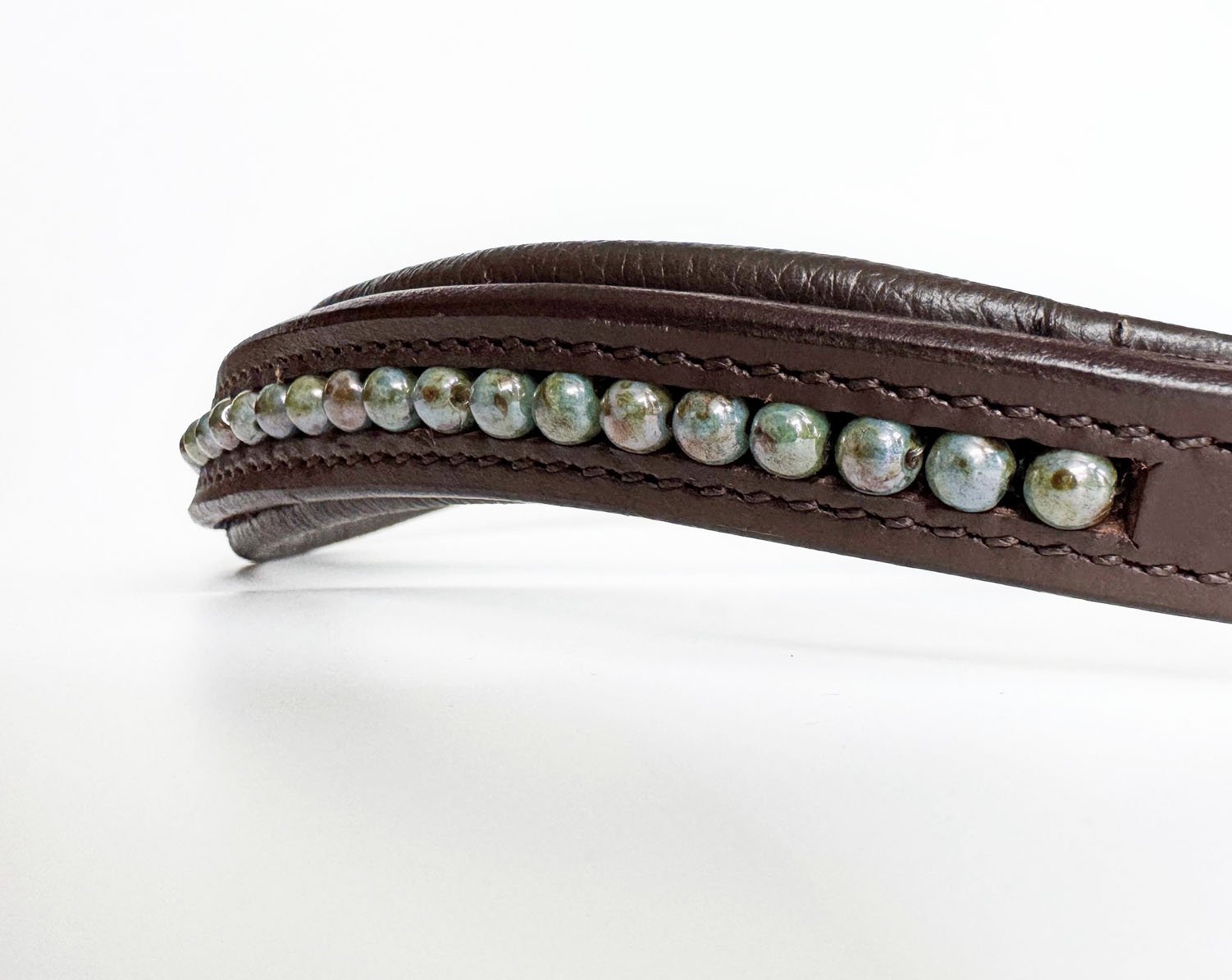 Close up of blue beads marbled with brown and green in a brown leather browband