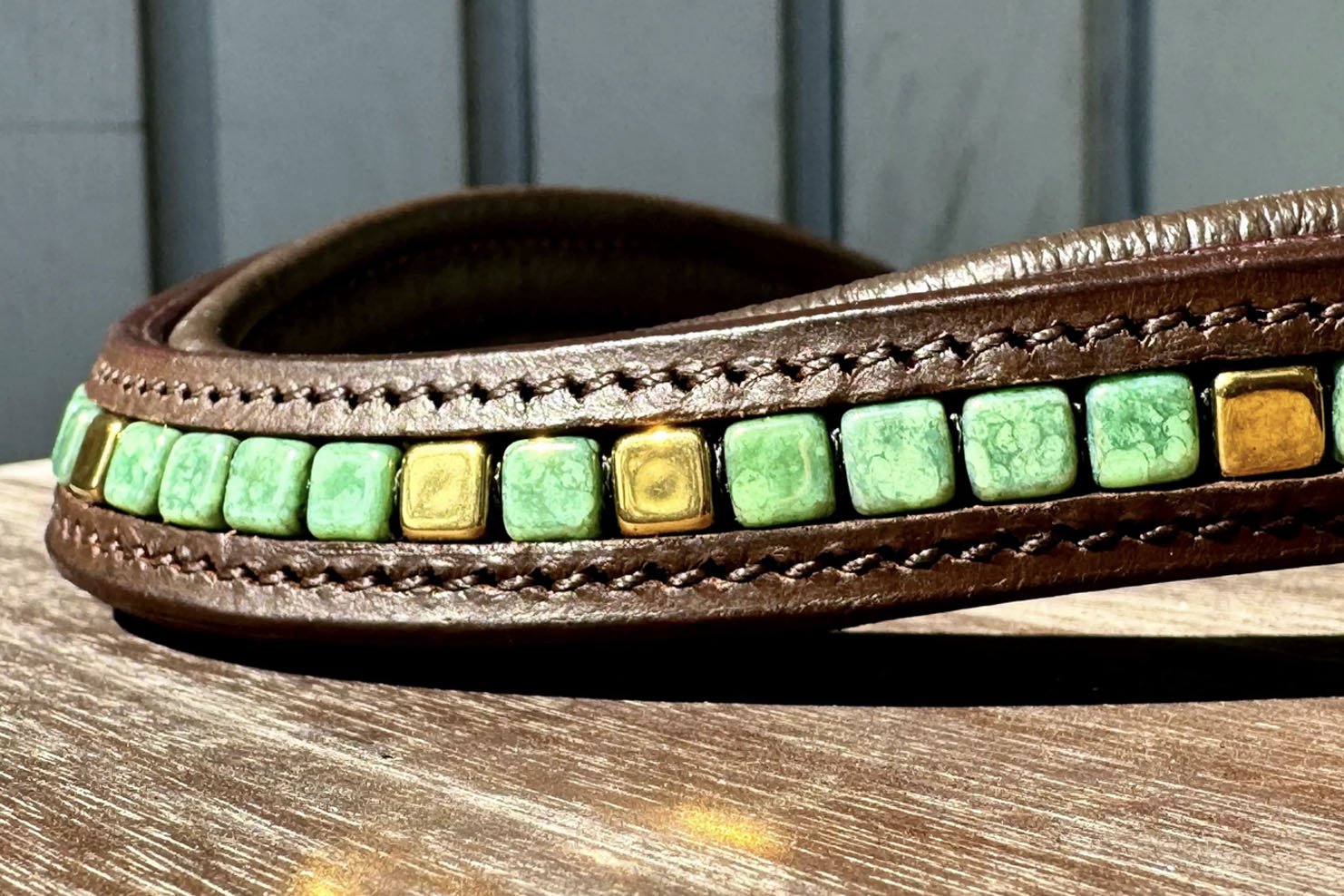Close up of green and gold beads in brown leather browband