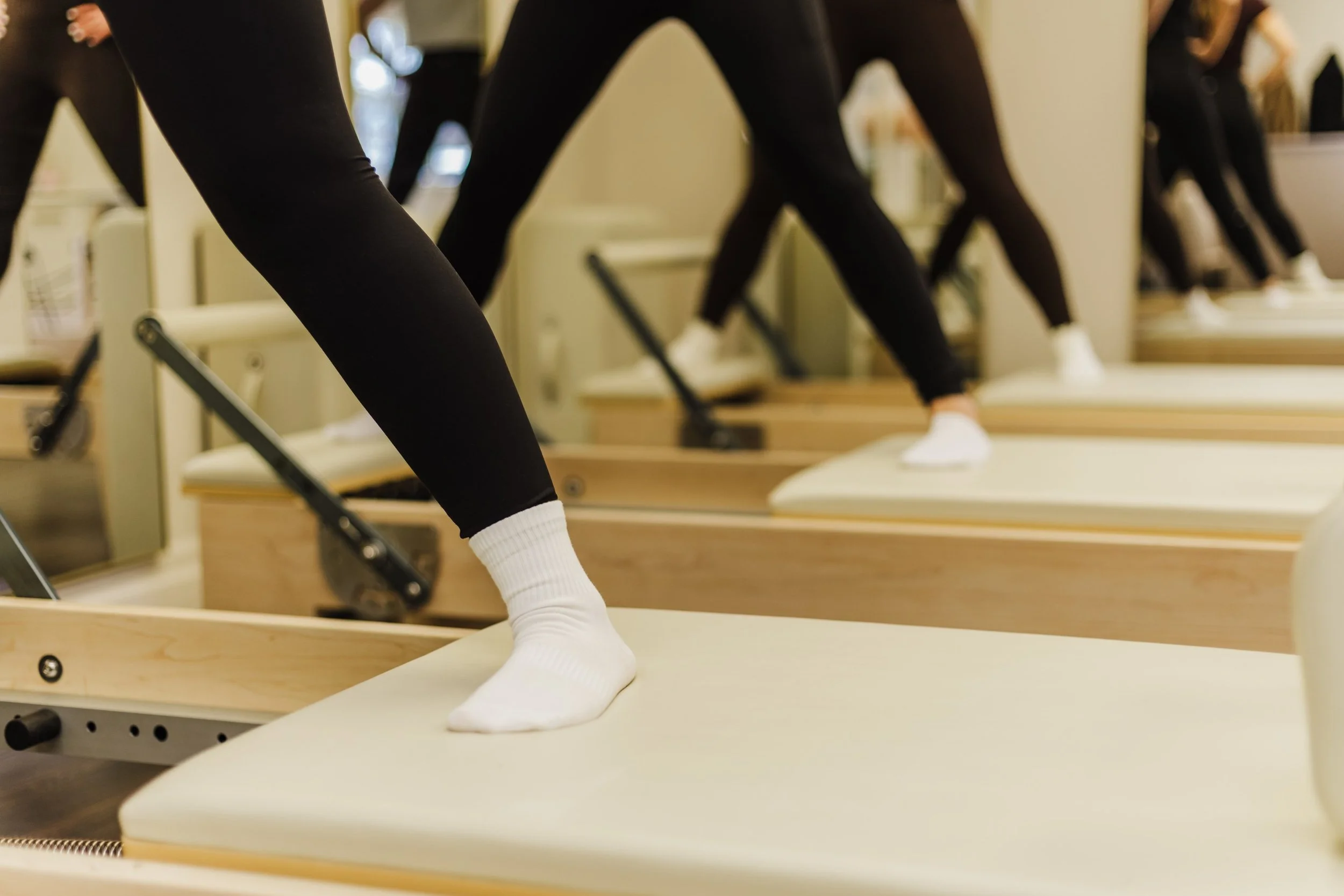 People exercising on reformer Pilates machines in a fitness class.