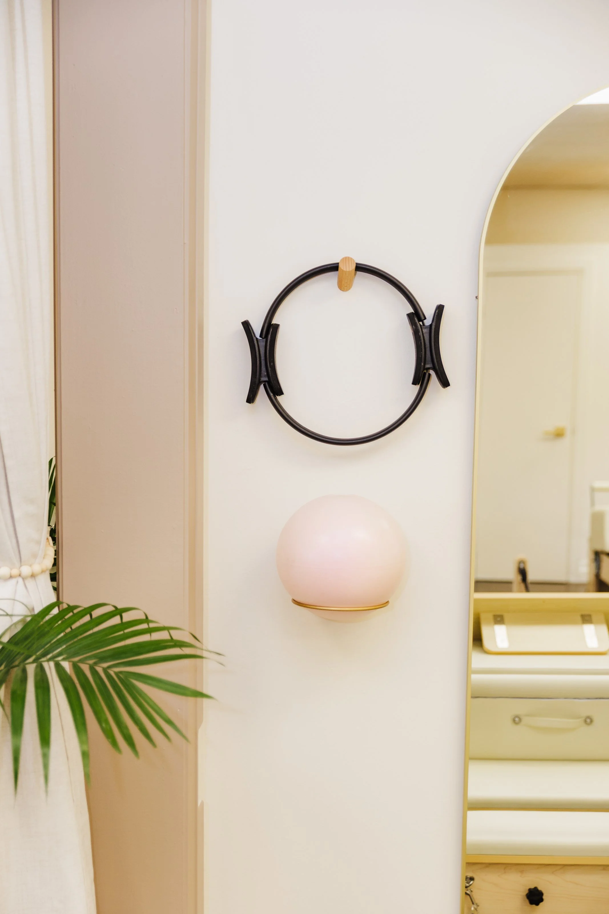 Decorative wall with a black circular wall piece, a pink spherical lamp, and a green plant partially visible.