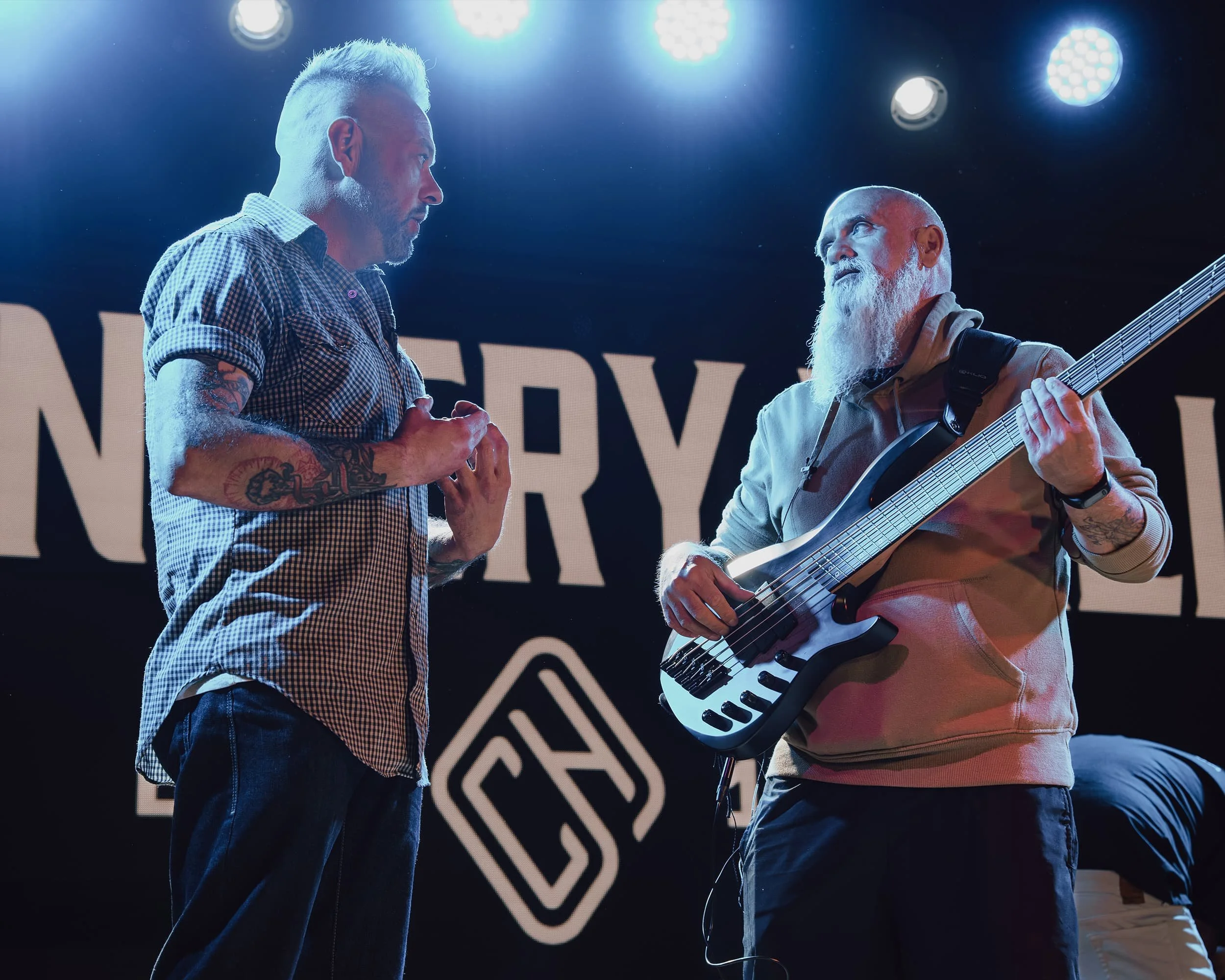 Two people talking onstage under blue stage lights.