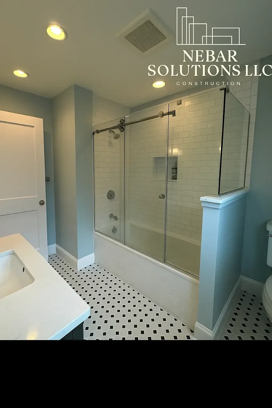 Bathroom with a glass shower enclosure, white subway tile walls, black and white patterned floor tiles, and a light blue wall. Logo of Nebar Solutions LLC Construction is overlaid at the top.