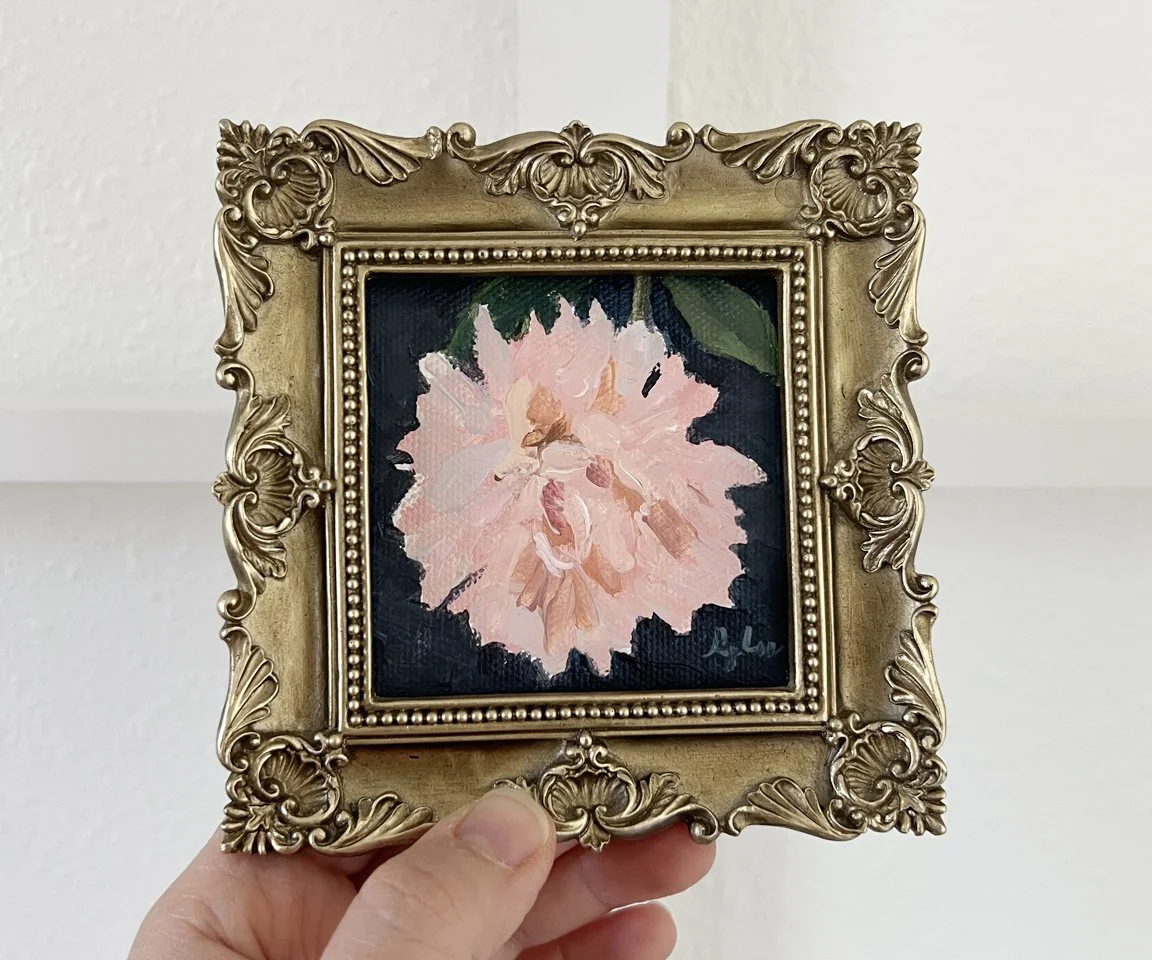 antique gold framed painting of pink astor mum with navy background against white wall