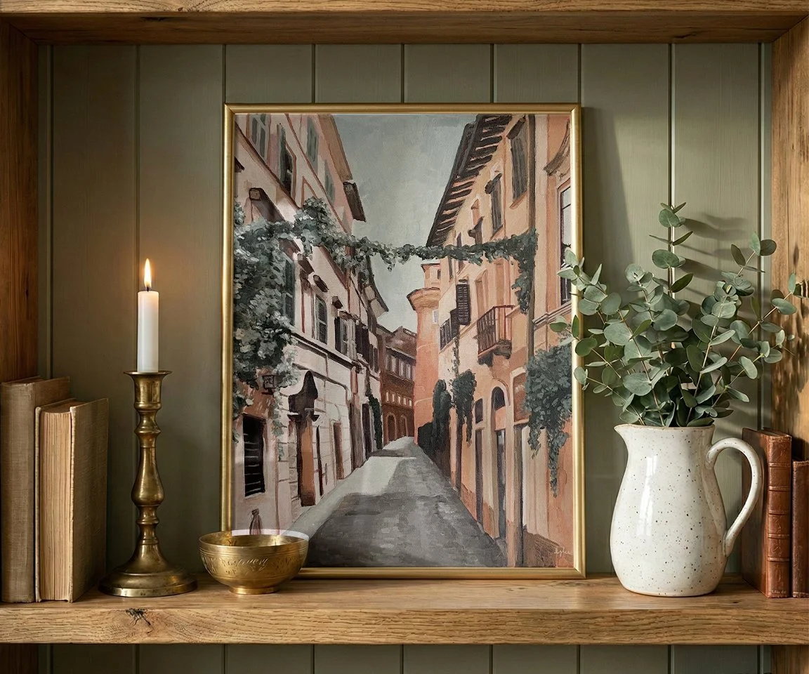 gold framed painting of cobblestone road in Rome on bookshelf