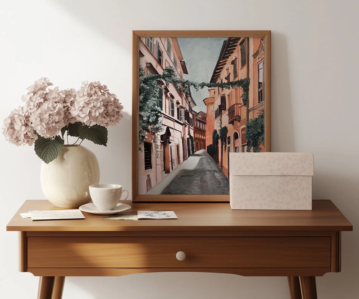 framed painting of road in Rome sitting on desk