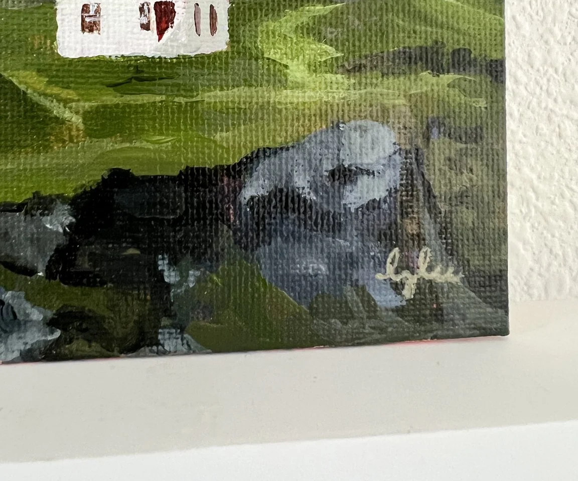 detail image of artist signature on rocky cliff next to house