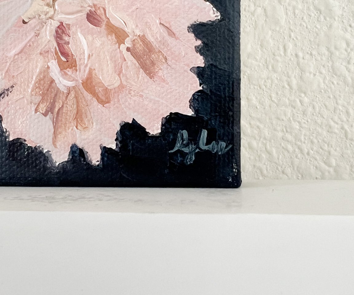 detail shot of artist signature on painting of pink astor mum with navy background