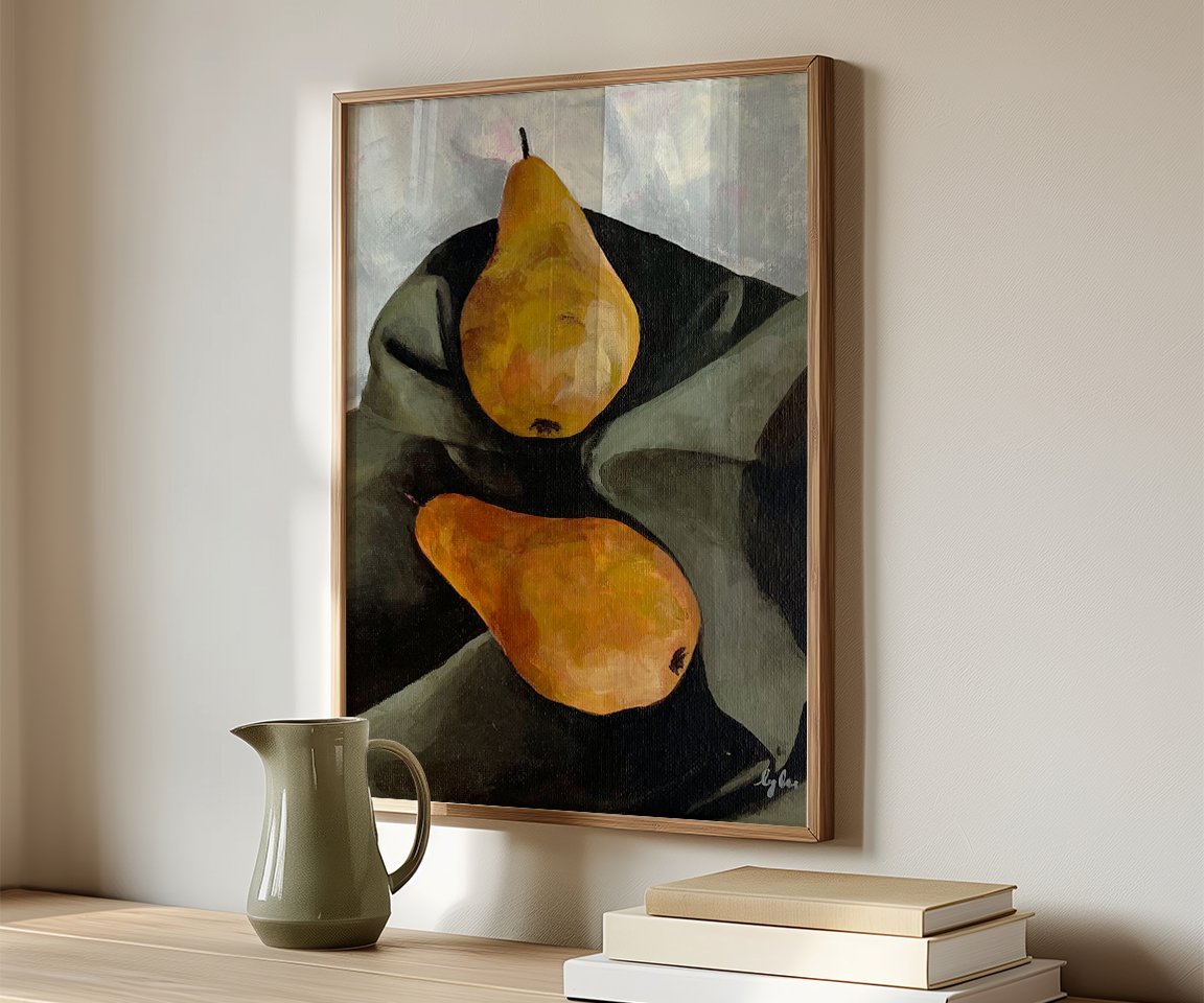 wood framed painting of two yellow pears on green sheet sitting on table with green pitcher