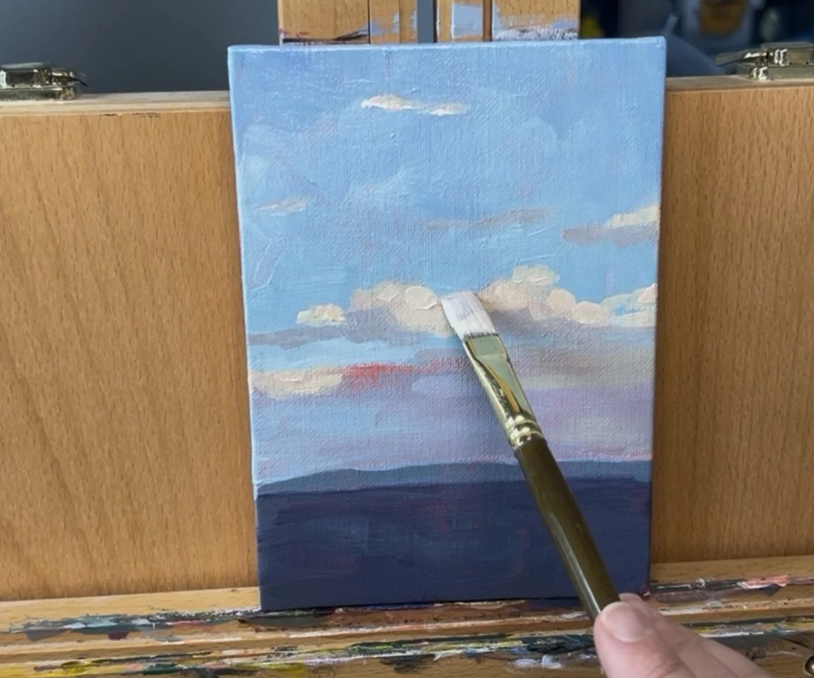 easel holding painting in progress of clouds in blue sky