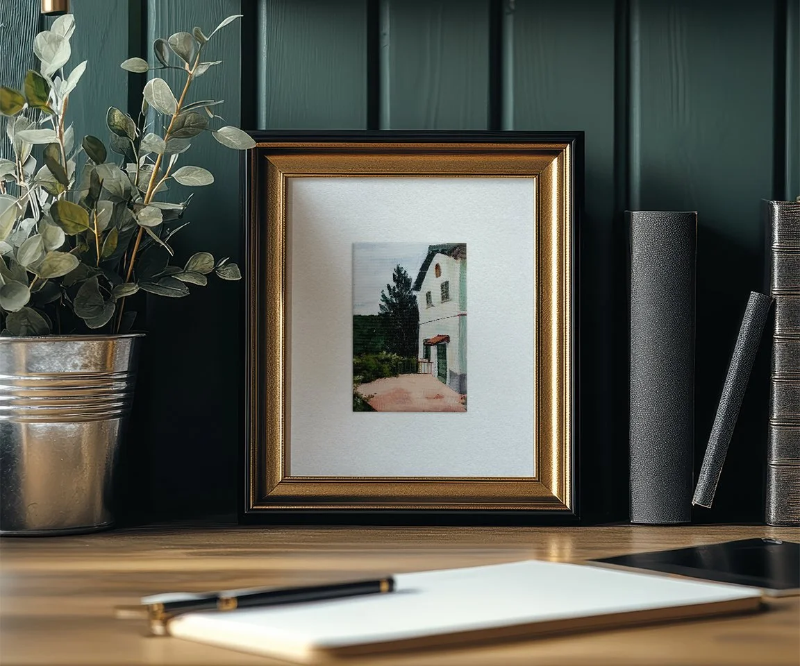 framed painting of Italian villa on desk