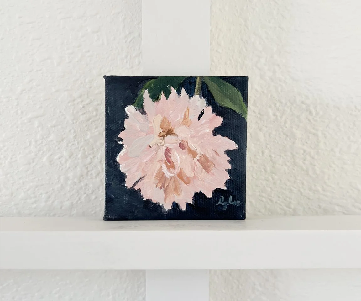 painting of pink astor mum with navy background set on white shelf and wall