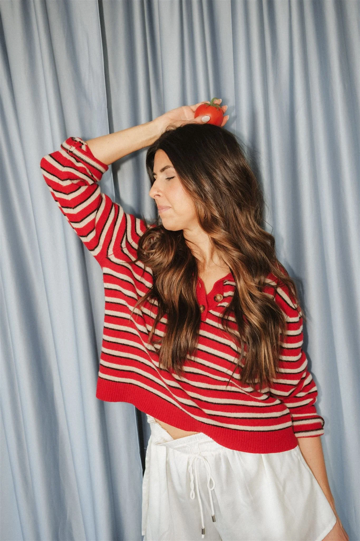  A woman holding a tomato above her head as a fun brand photoshoot idea. 
