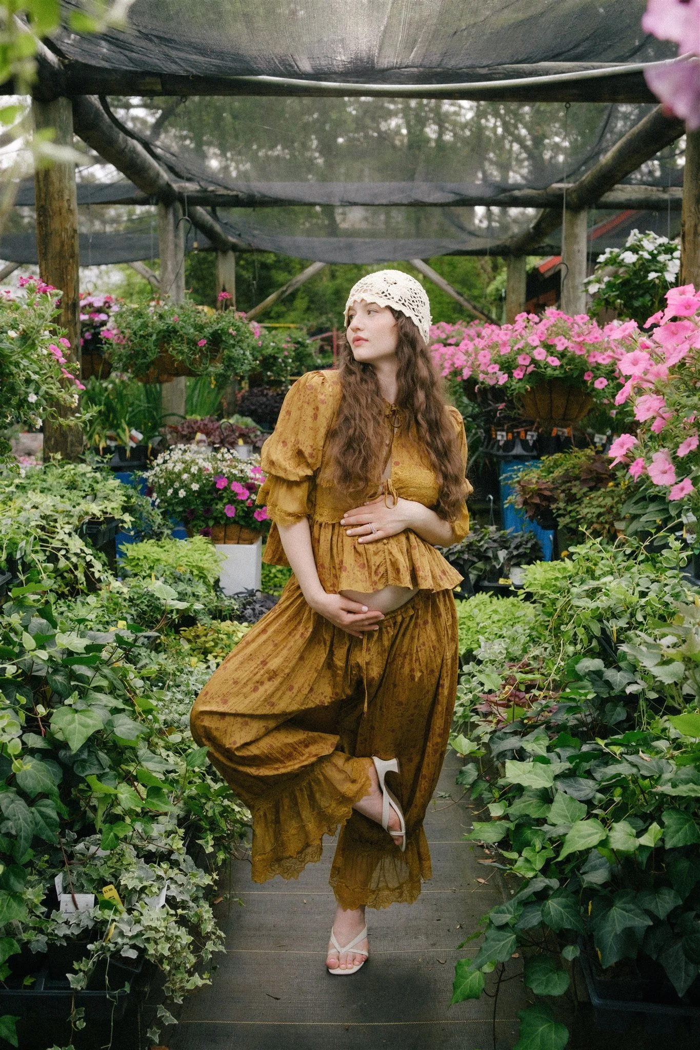 A pregnant woman standing in an aisle of plants. 