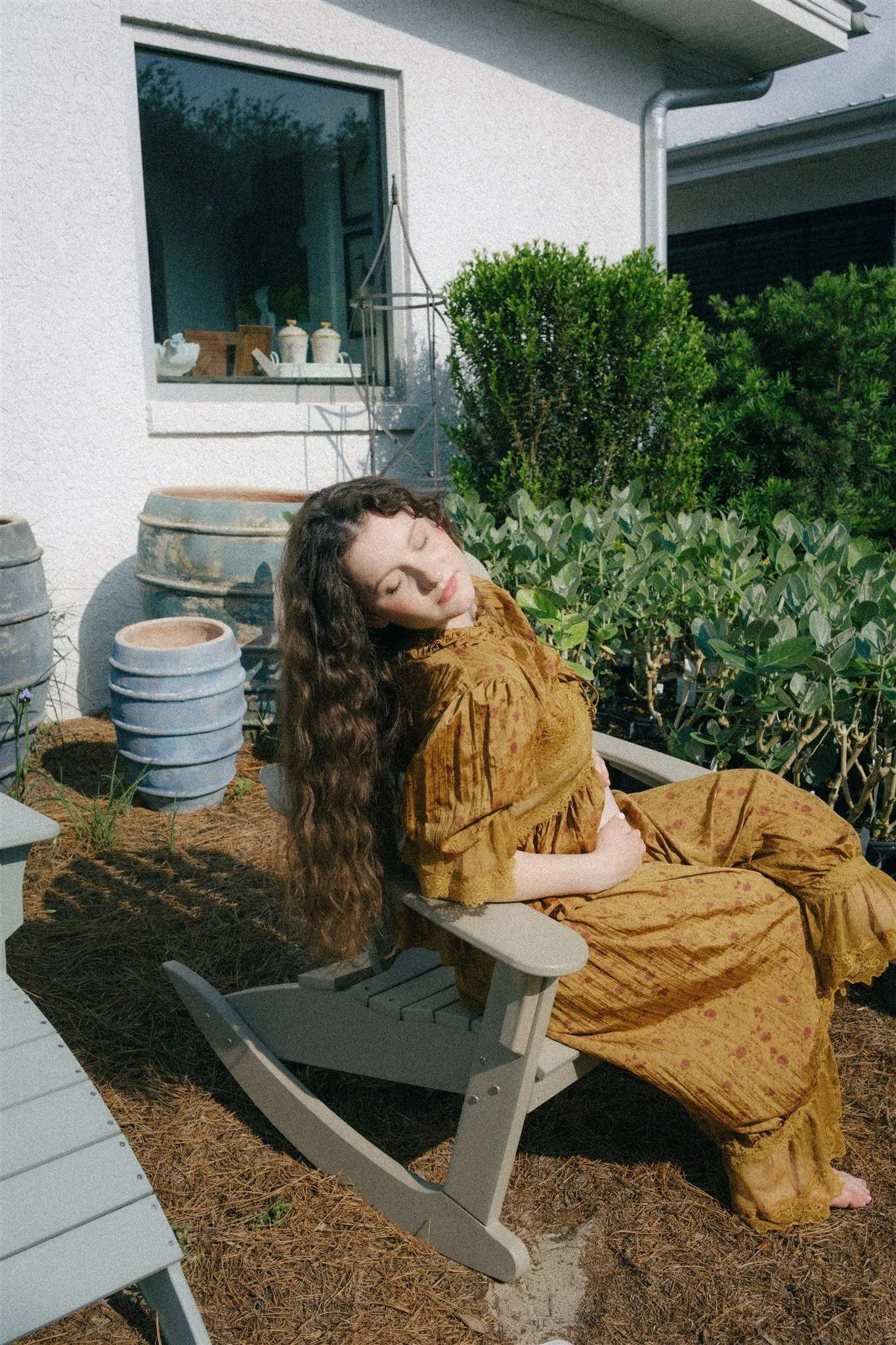  A woman sitting outside of a flower shop in a chair.  