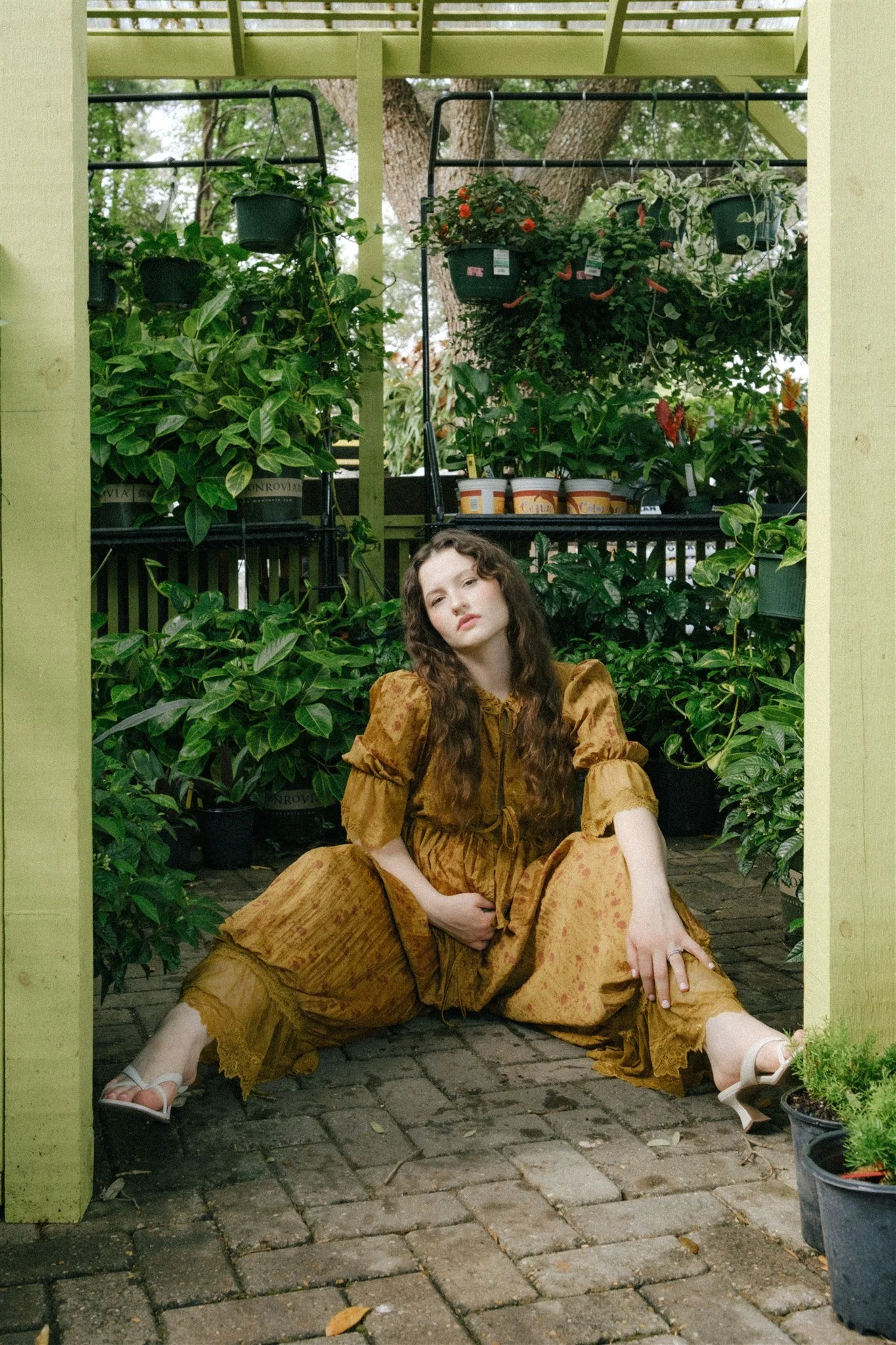  A business owner sitting on the ground of a flower shop for her brand photoshoot. 
