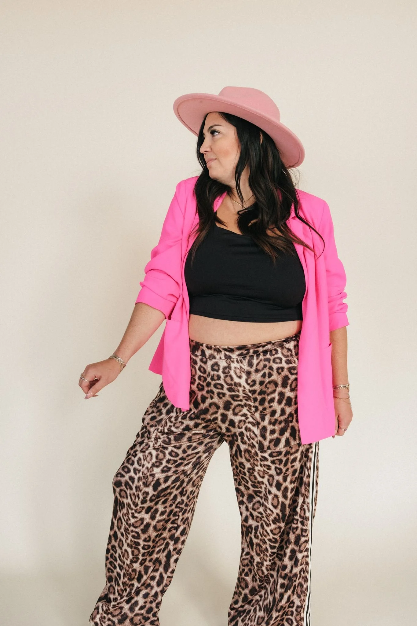  A business owner posing for brand photography in cheetah print pants and a pink cowgirl hat.  