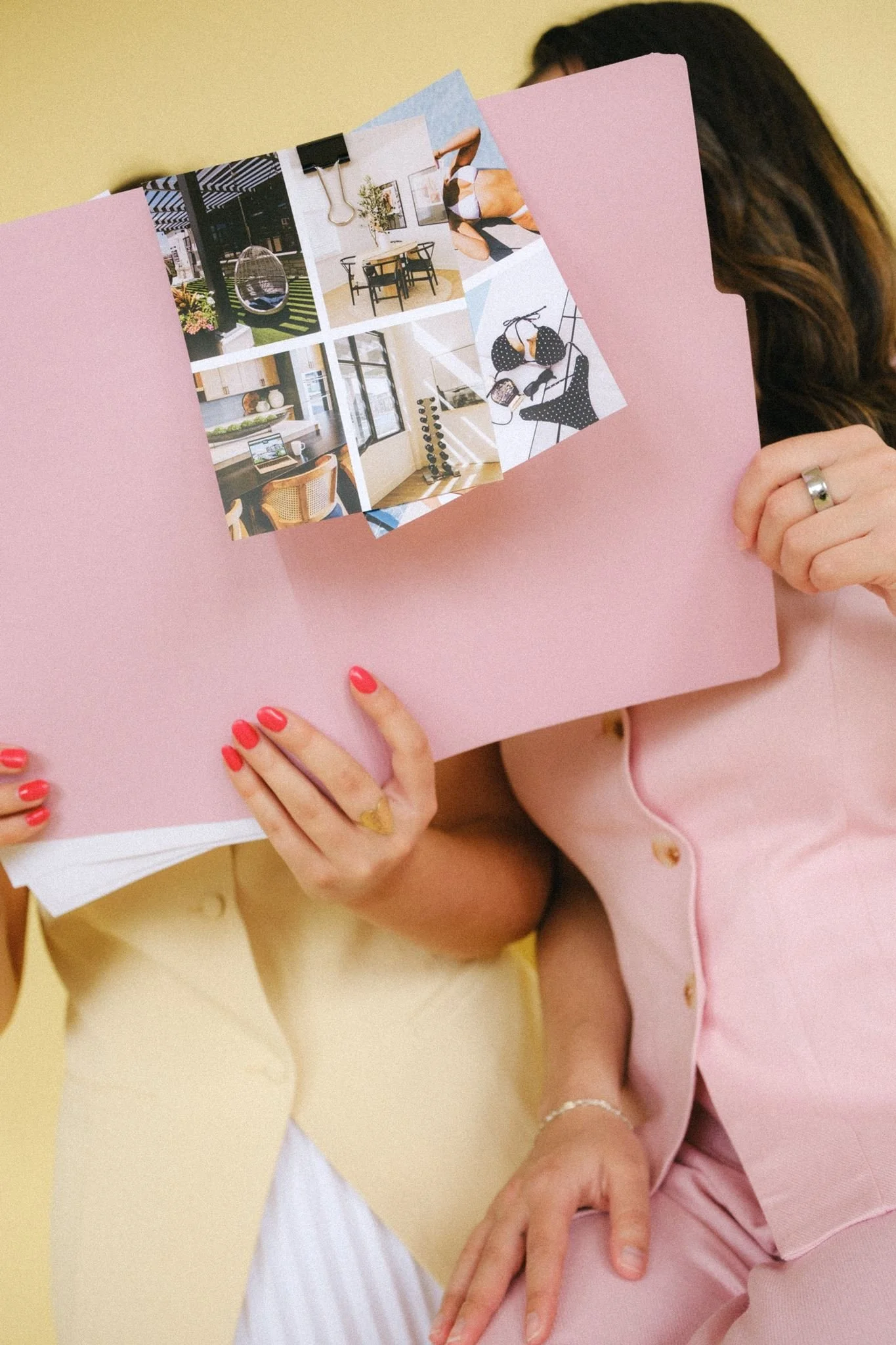  Two women looking at their photoshoot props of a pink folder and brand imagery.  