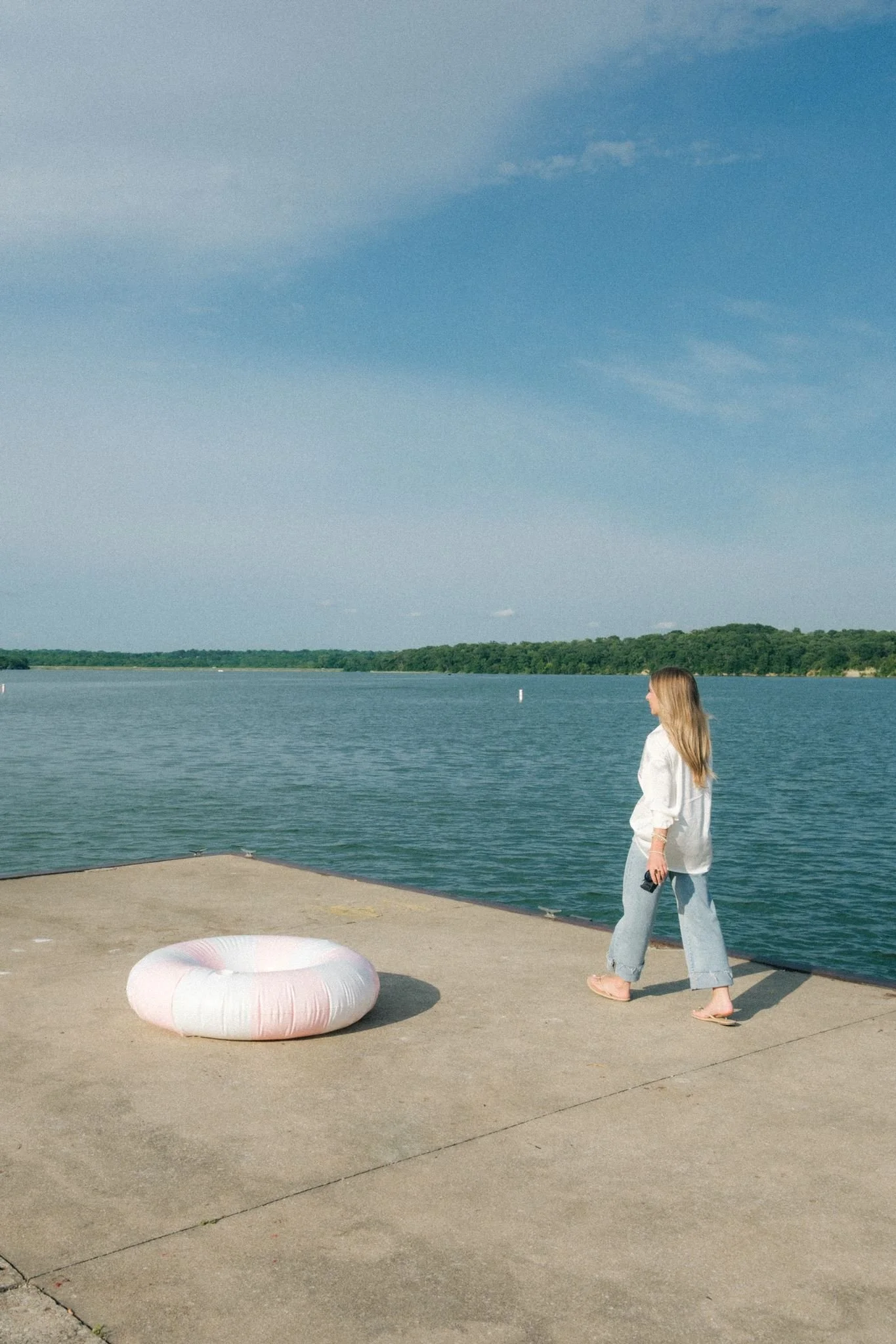  A woman walking towards the water with a pool float as a brand photo prop. 