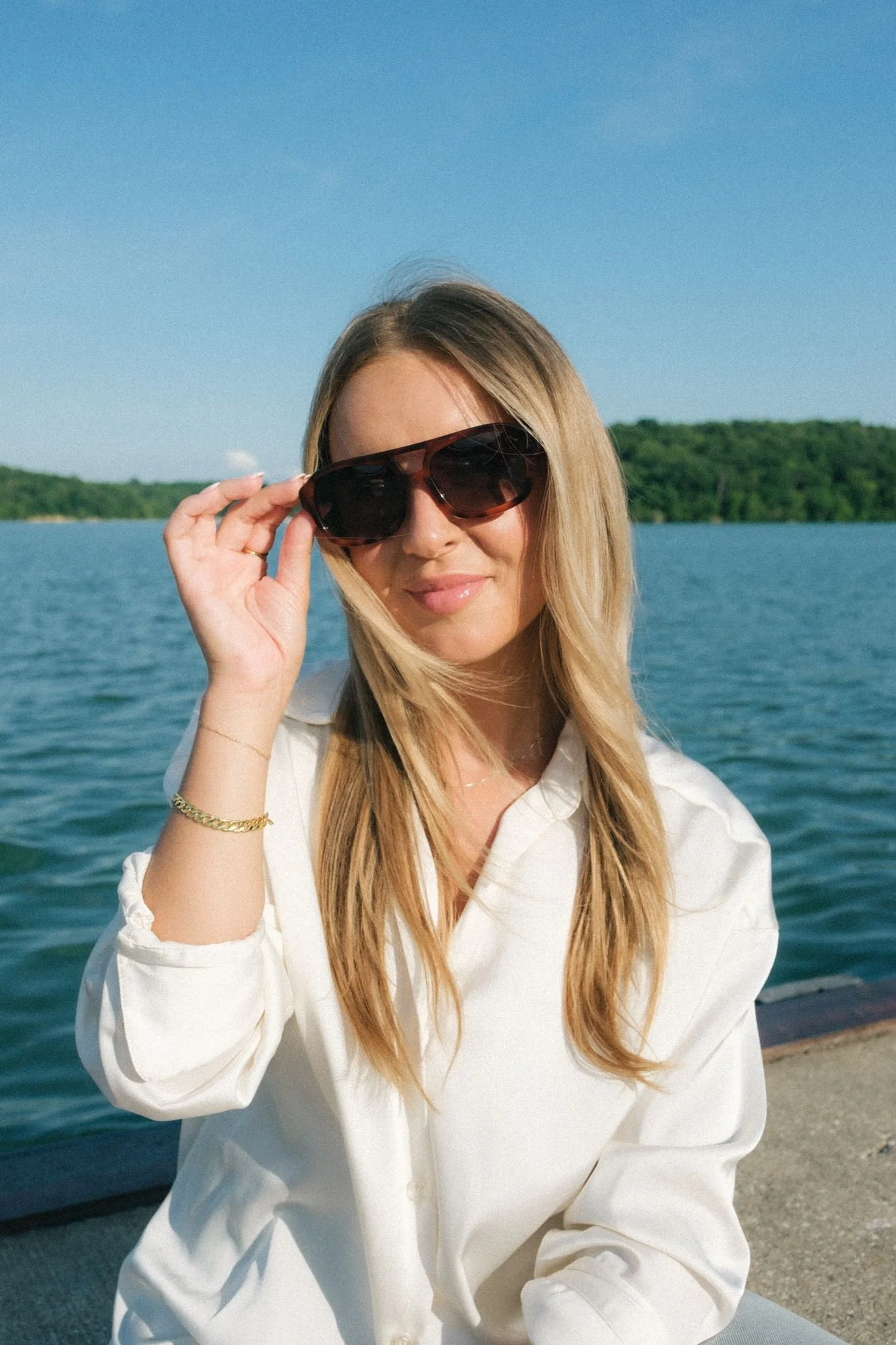  A woman wearing sunglasses by the water. 
