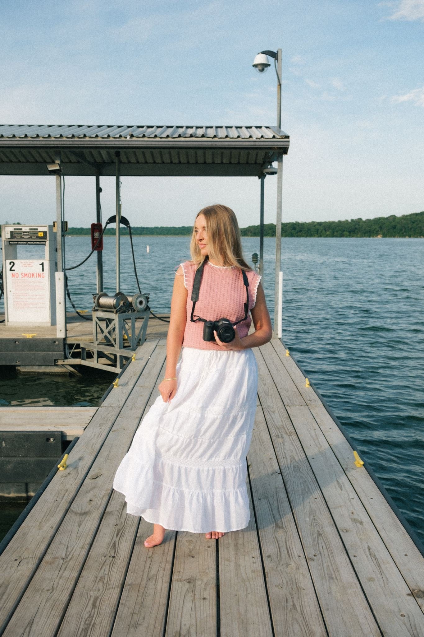  A woman holding a camera while looking towards the water. 