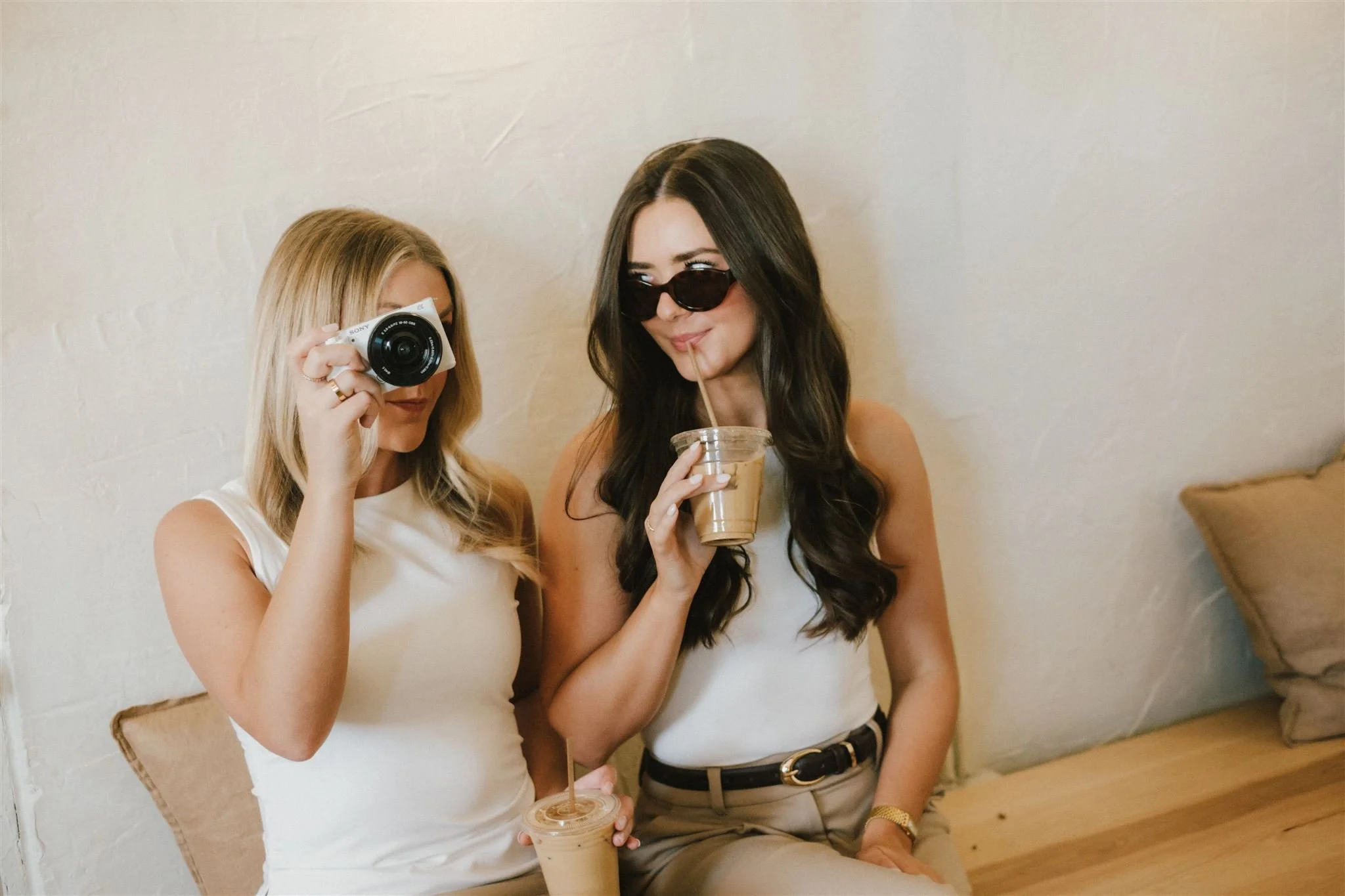 Two women holding a camera and coffee as props for their brand photoshoot in KC.