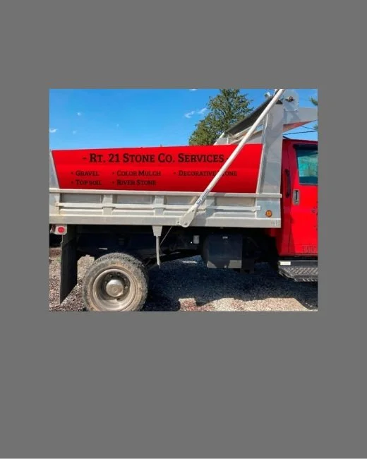 Red truck with "RT. 21 Stone Co. Services" sign offering gravel, color mulch, decorative stone, top soil, and river stone.