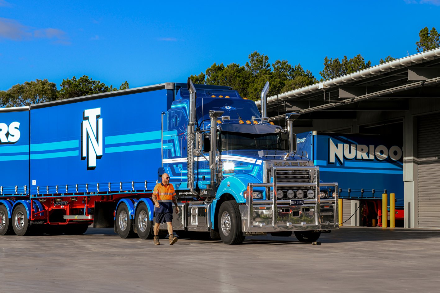 Nuriootpa Traders semi-truck parked outside a warehouse with a person in work clothes walking nearby.
