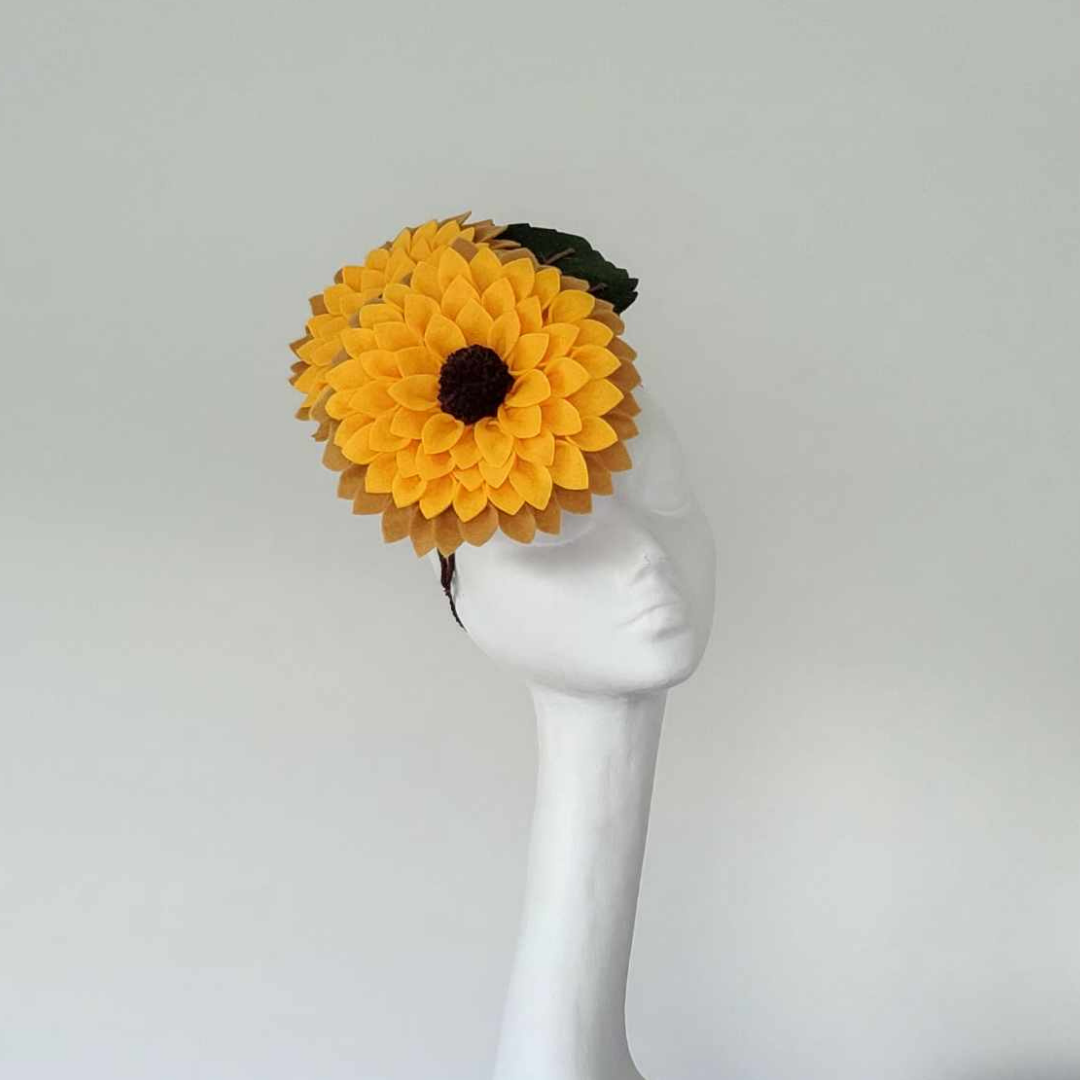 Handmade felt sunflower headpiece in yellow with brown centre and green leaves, worn with headband and elastic