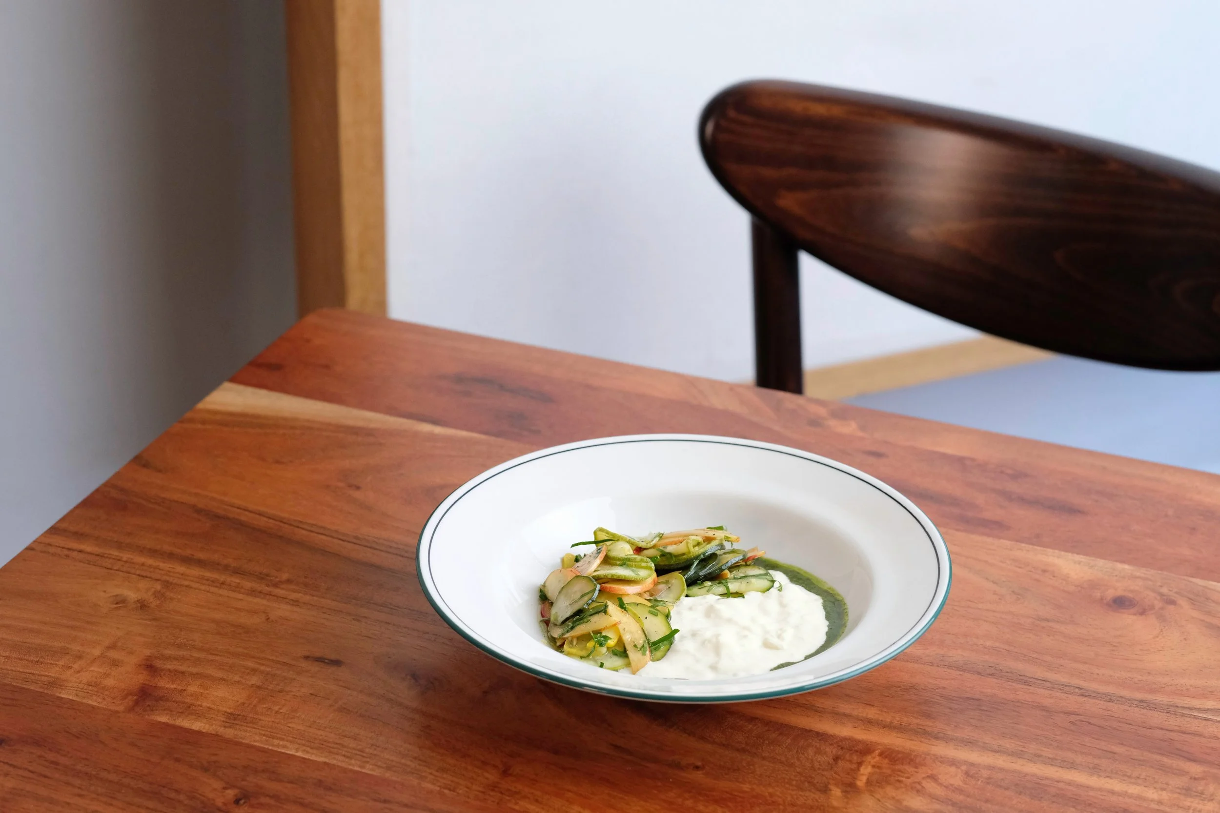 A plate of grilled asparagus spears topped with fresh herbs and yellow flower petals, served with a sauce or puree underneath.