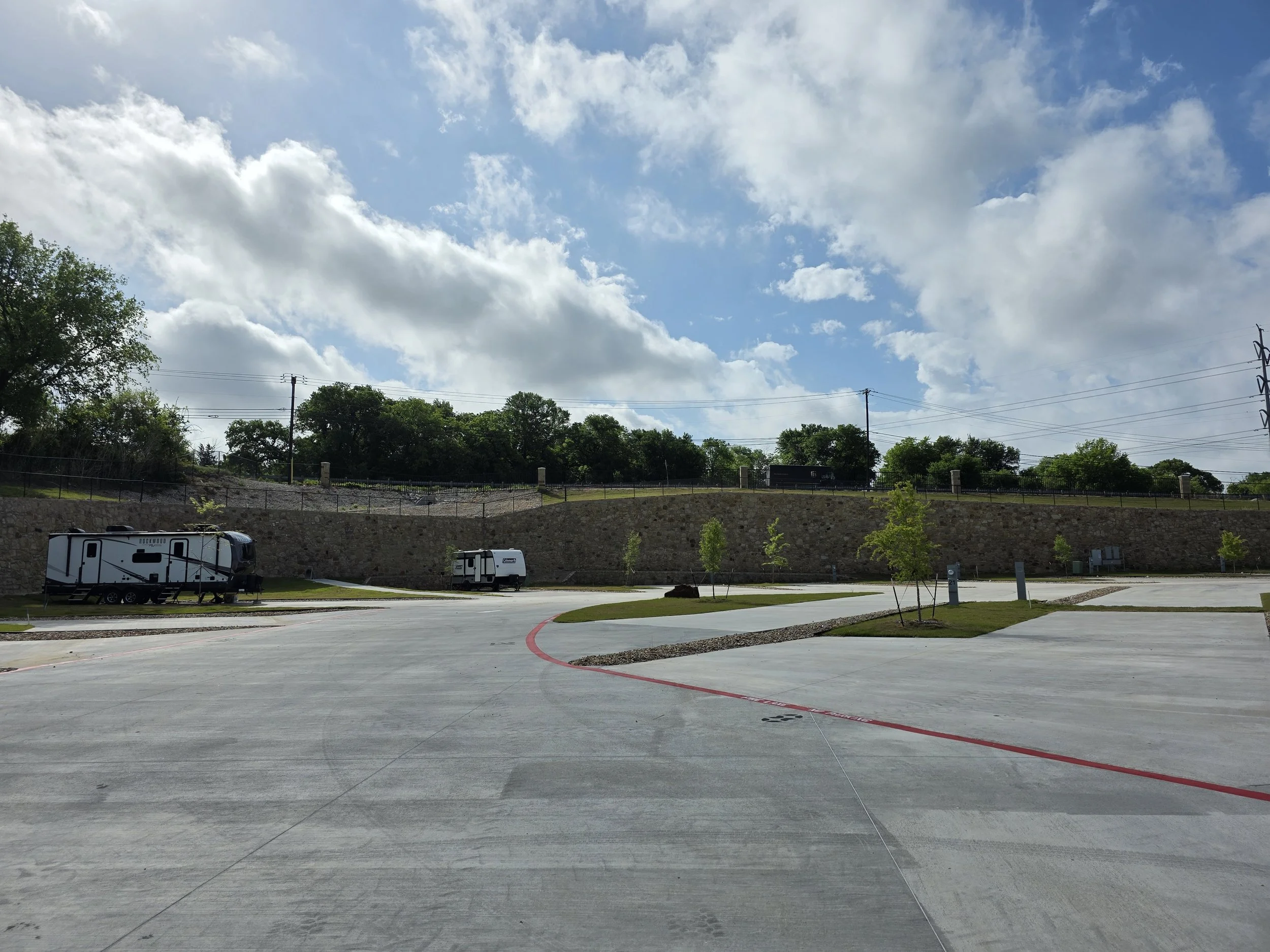 RV in background, looking out over concrete drive and padsides near front of RV resort.