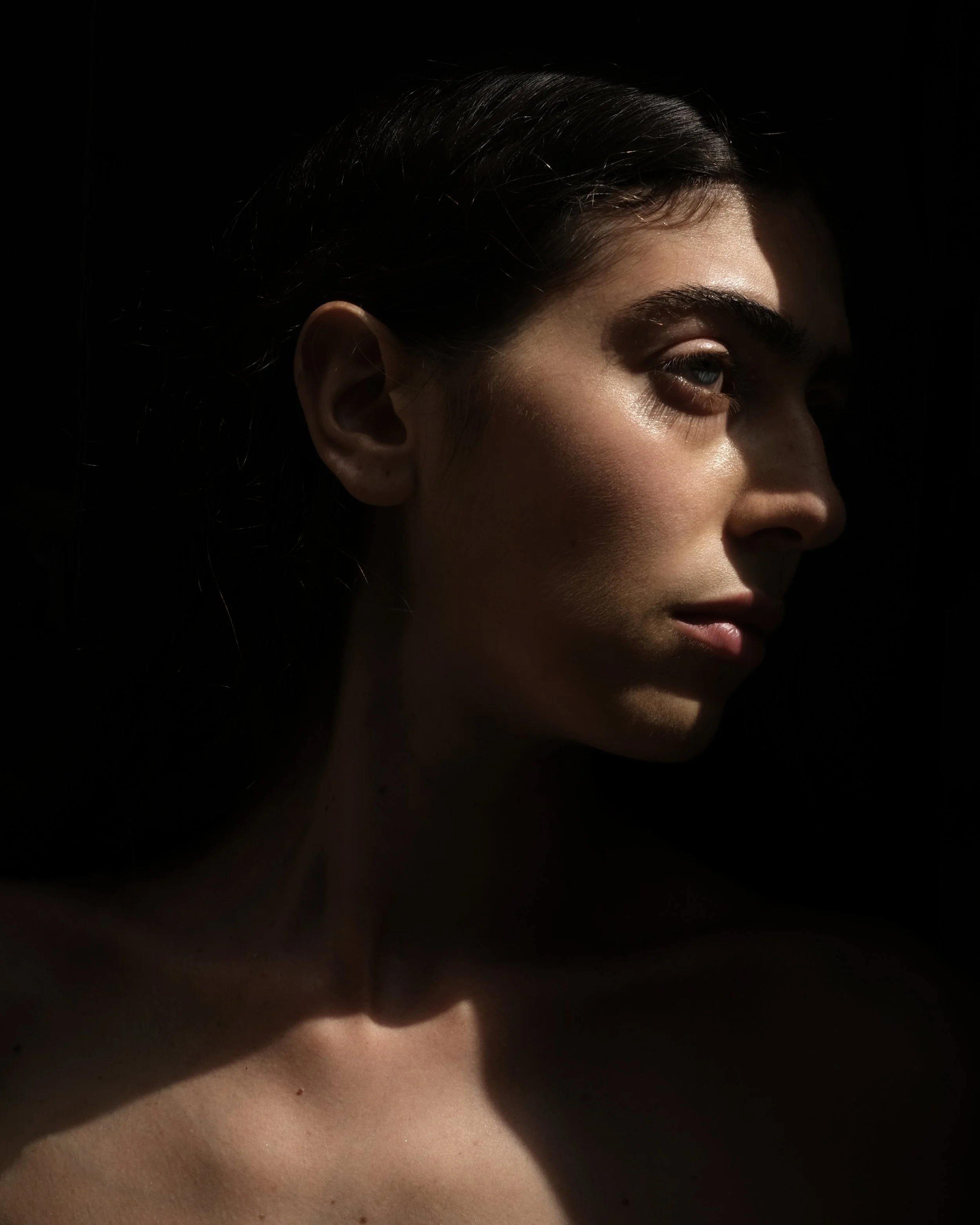 Ritratto di profilo di una donna in controluce, con un'illuminazione drammatica sul viso.