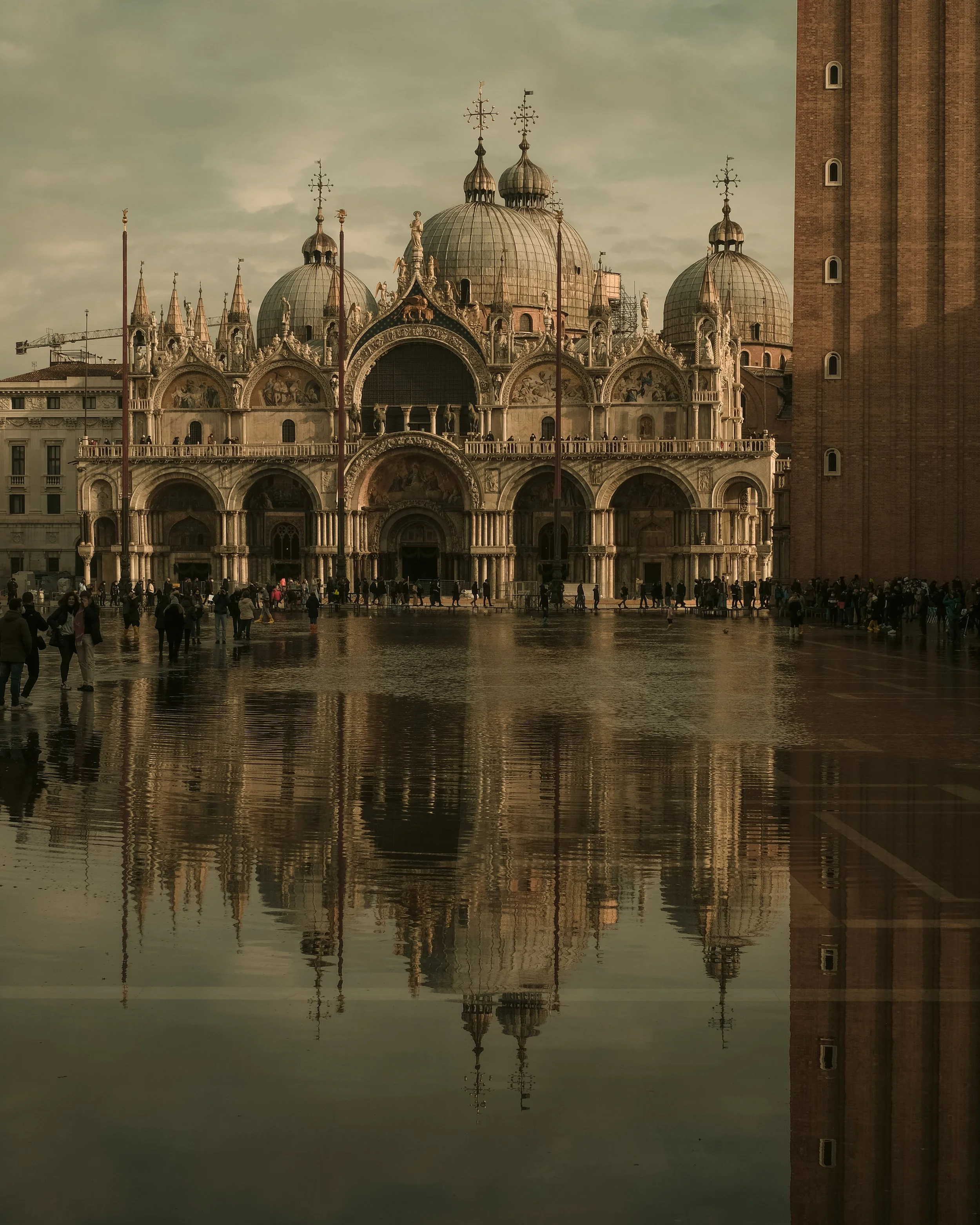 Il Duomo di Venezia con il suo riflesso nell'acqua, molte persone in piazza